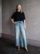 Image featuring a woman wearing the 100% cotton rigid jeans by Re/Done with a high rise, wide leg and cropped length in Bella Rosa wash.