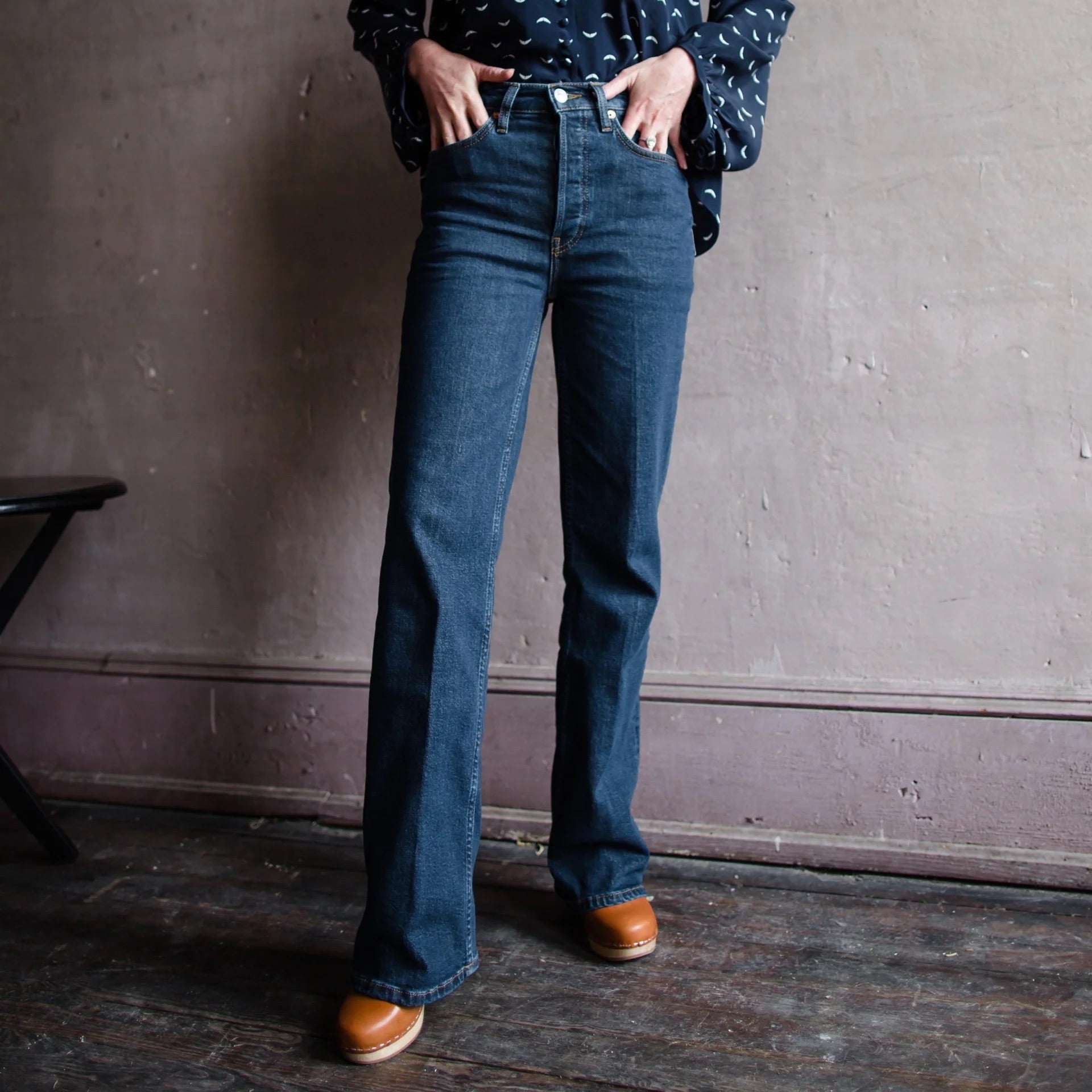 Image featuring a woman wearing the 70s Bootcut in Dark Rinse from Re/Done with a classic bootcut and long inseam with comfort stretch denim, a classic button fly, a finished hem.