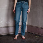 Image featuring a woman wearing the 70s Comfort Stretch High Rise Stove Pipe straight leg jean with cropped inseam. Features a classic button fly, and a raw hem