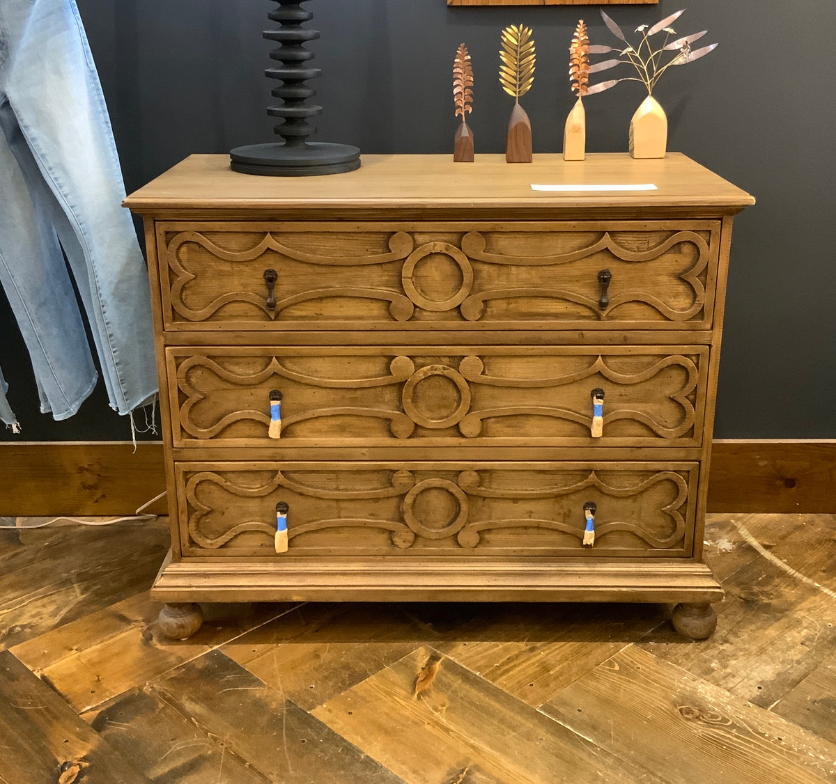 A wooden three-drawer dresser with intricate carvings on the drawers. hand crafted in USA with reclamed douglas fir wood