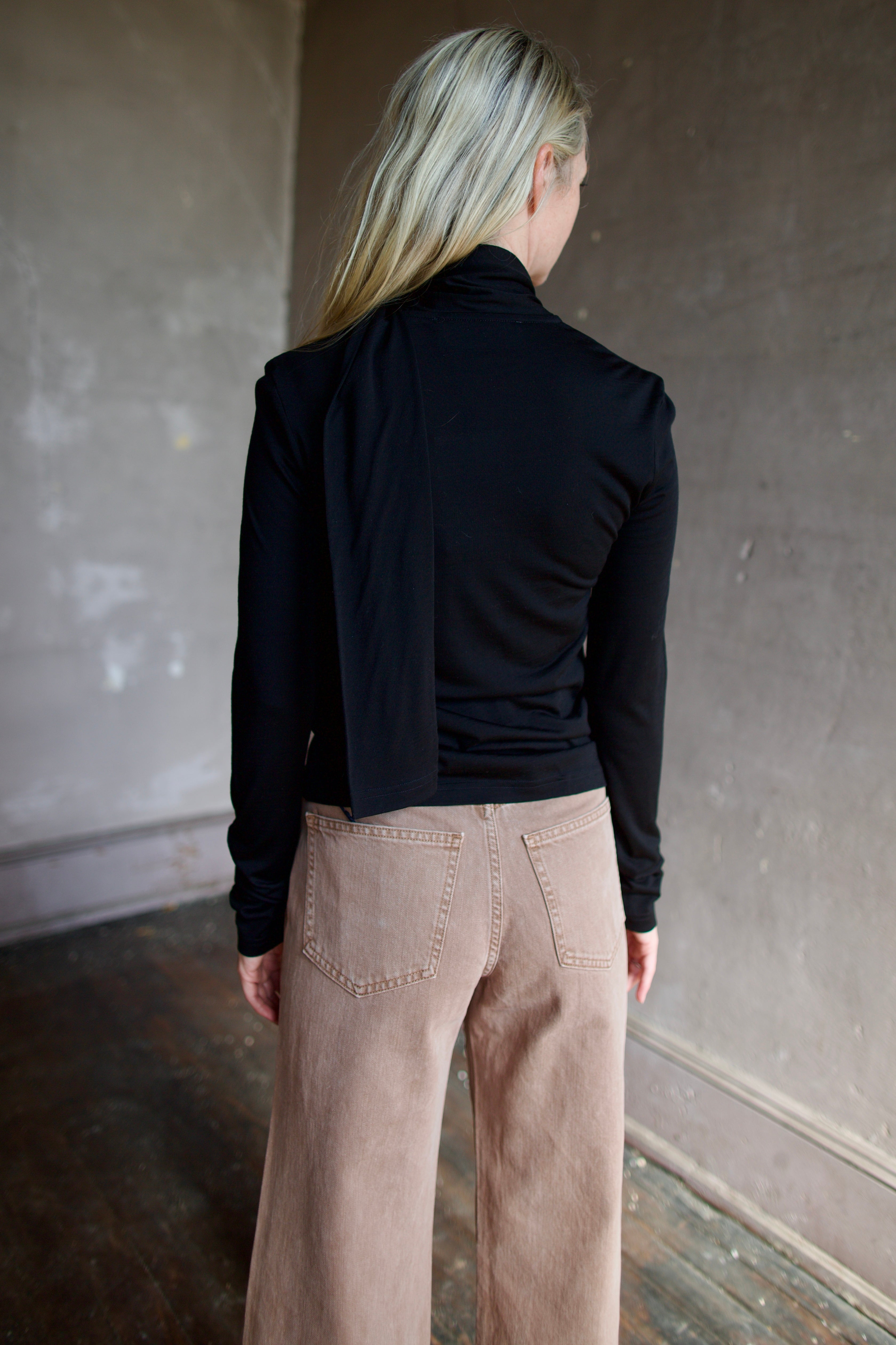 Model wearing a premium merino wool black top by luxury Amsterdam designer Rohe with integrated scarf for an quality elevated basic