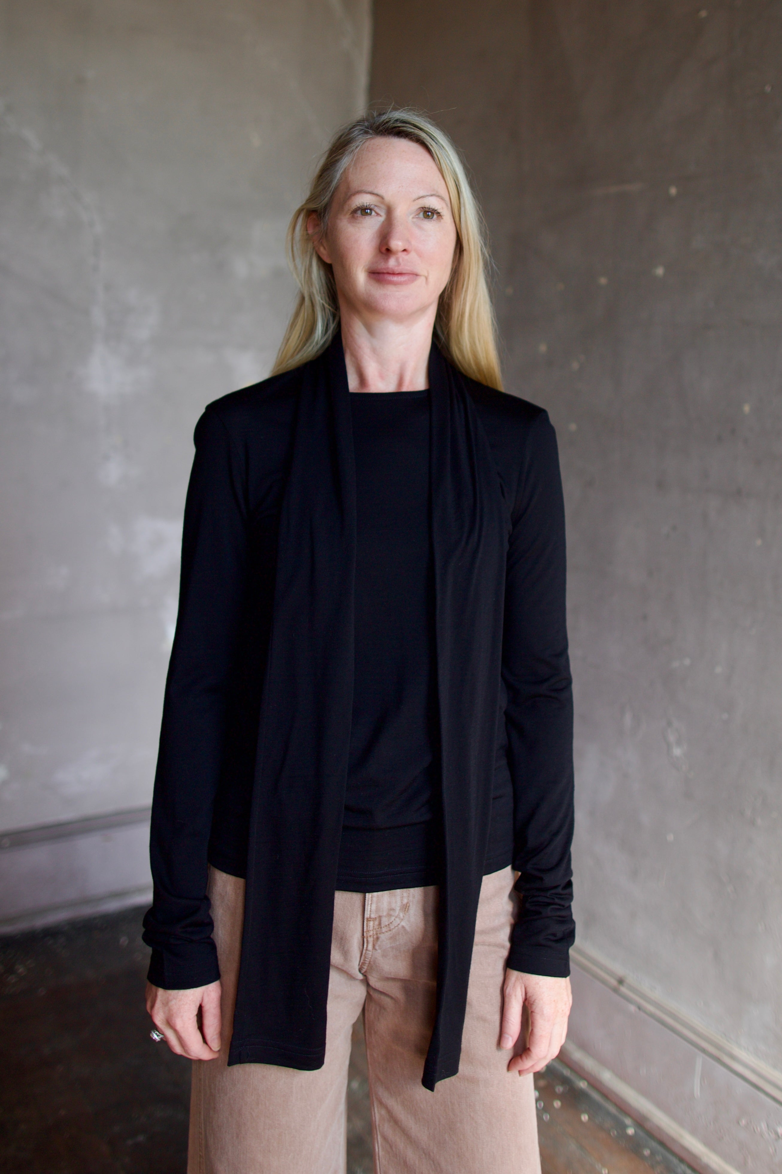 Model wearing a premium merino wool black top by luxury Amsterdam designer Rohe with integrated scarf for an quality elevated basic