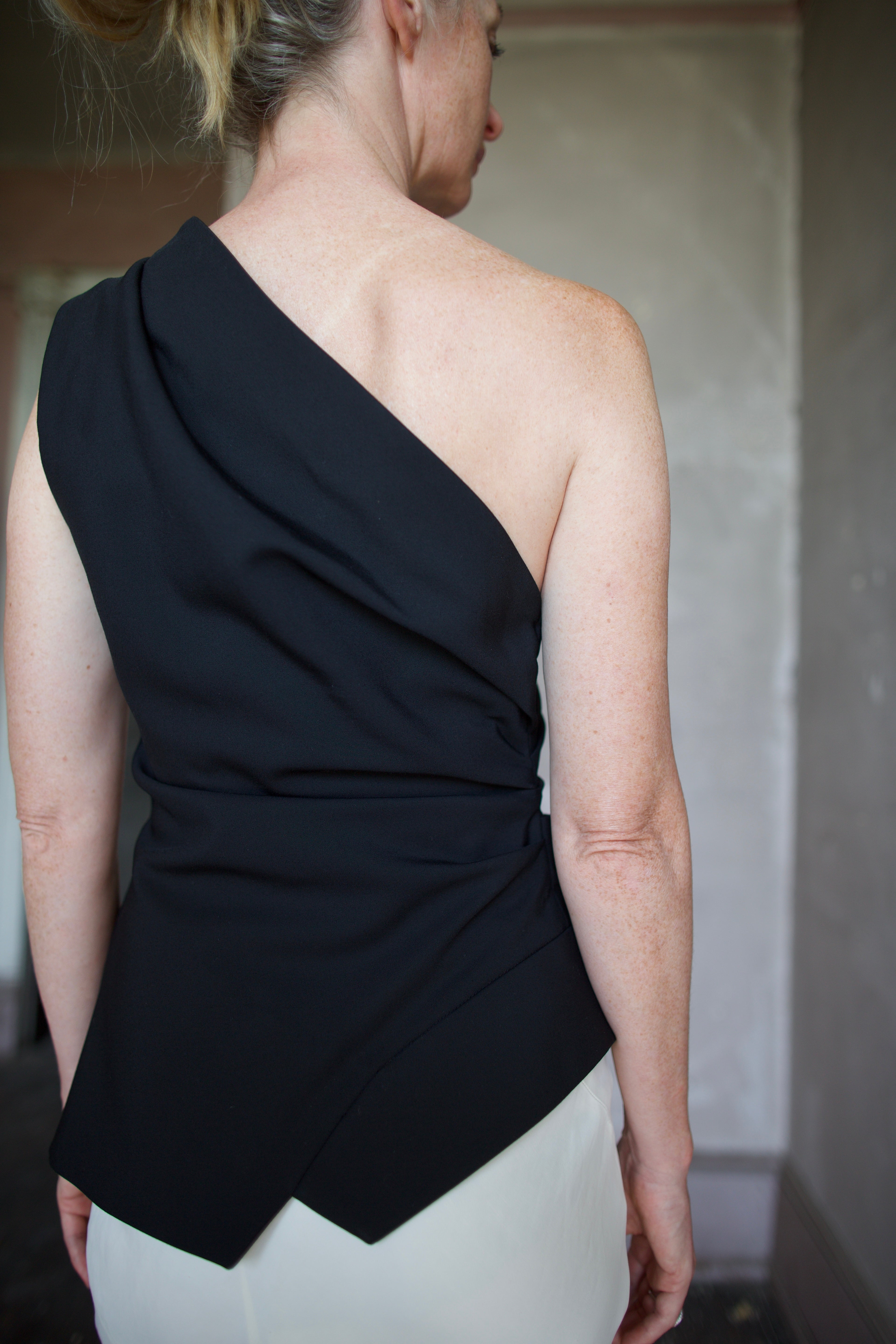 Model wearing luxury modern designer brand Rohe flattering off shoulder lapel top in black 