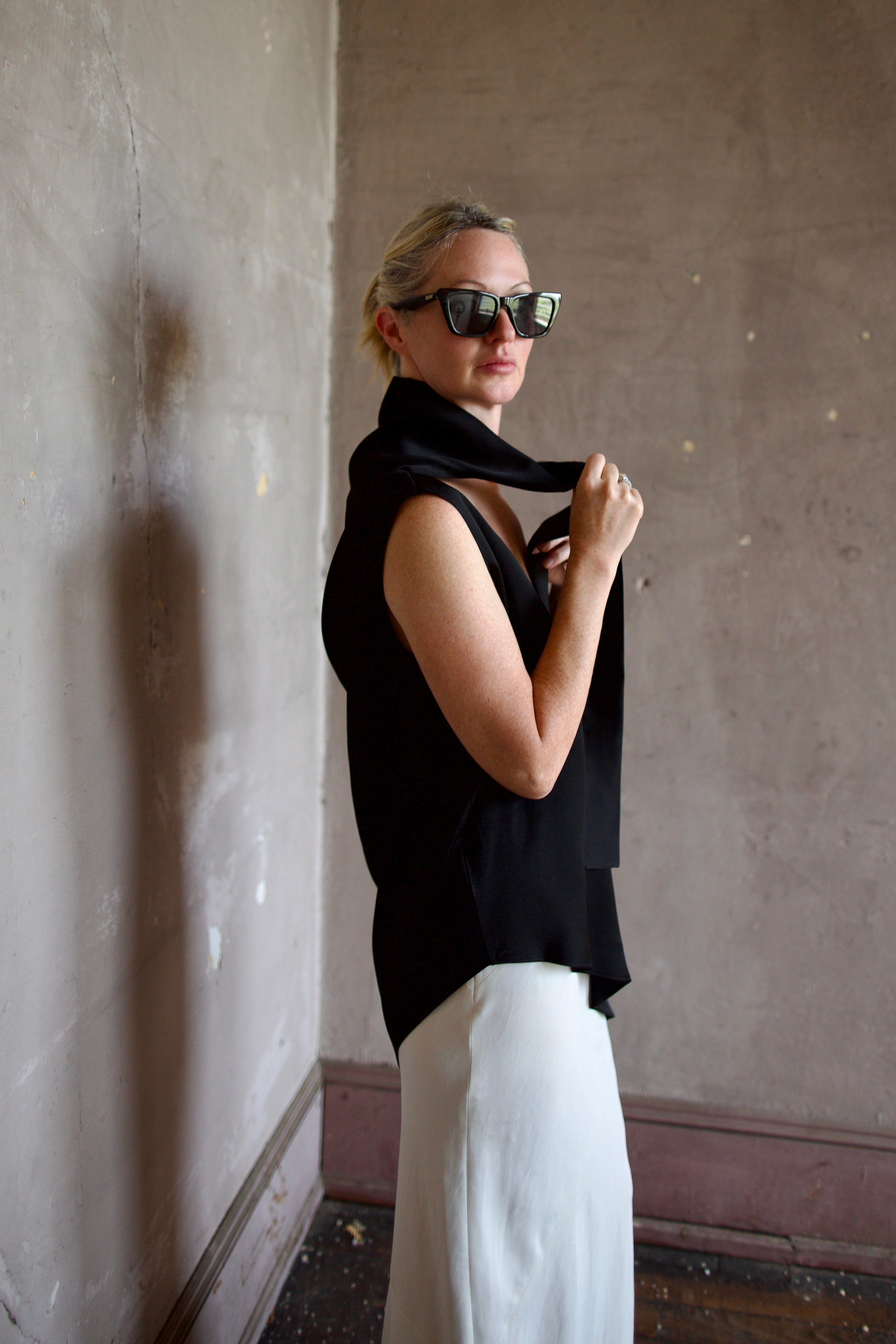 Model wearing black sleeveless satin top with expertly crafted draping and attached tie by luxury modern designer Rohe