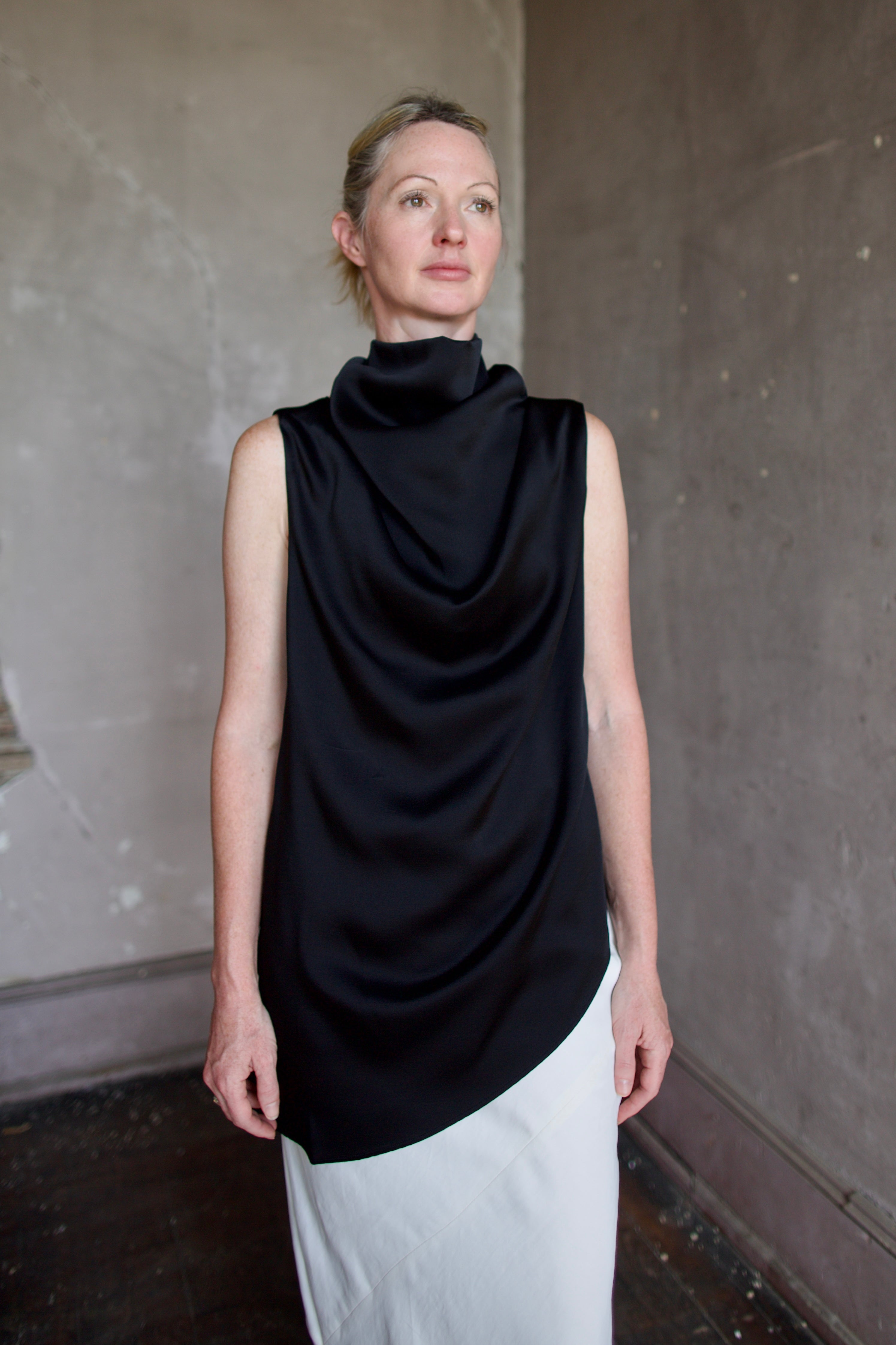 Model wearing black sleeveless satin top with expertly crafted draping by luxury modern designer Rohe