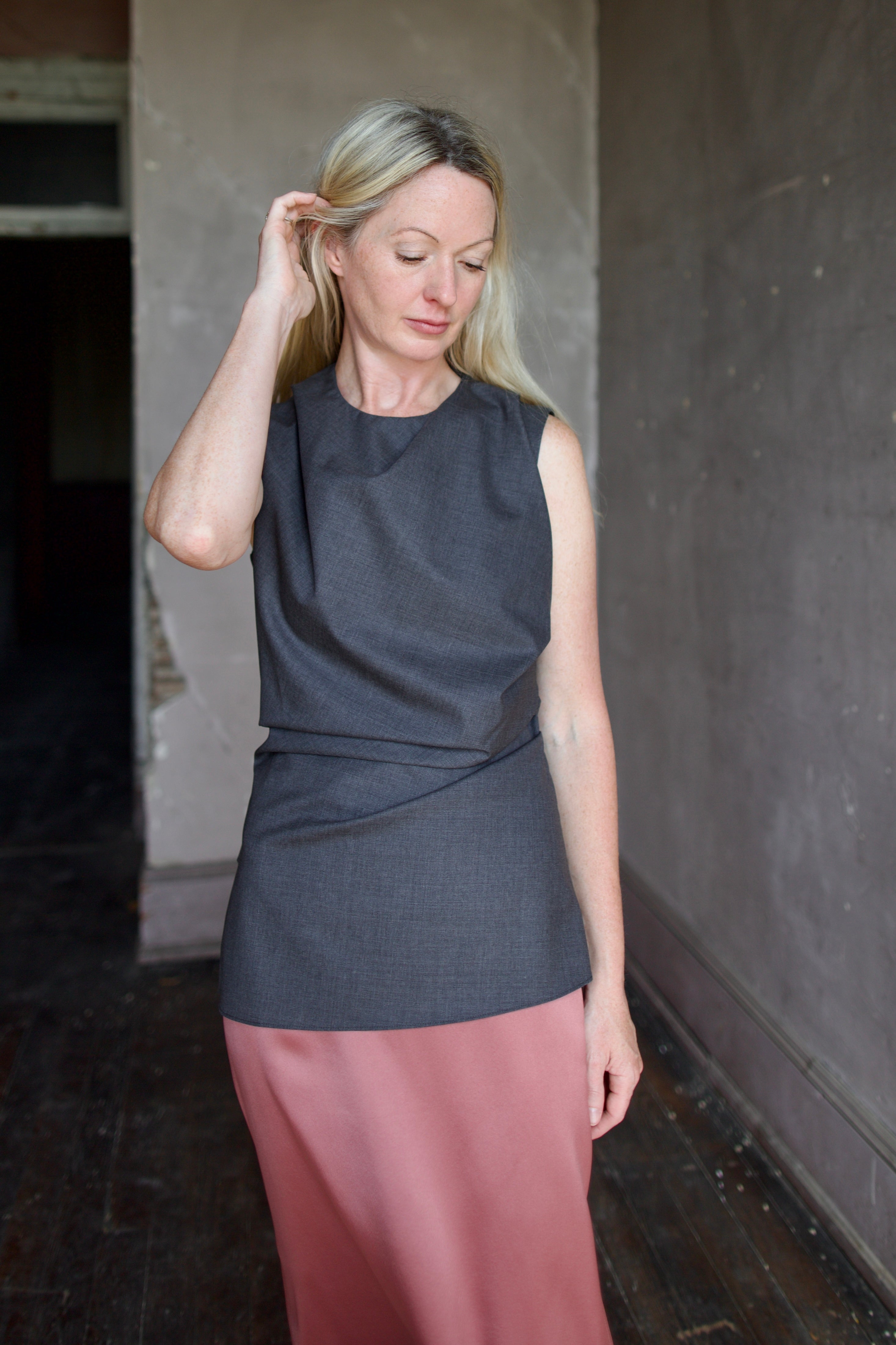 Model wearing luxury designer Rohe sleeveless twisted top in dark grey combining refined tailoring with contemporary comfort