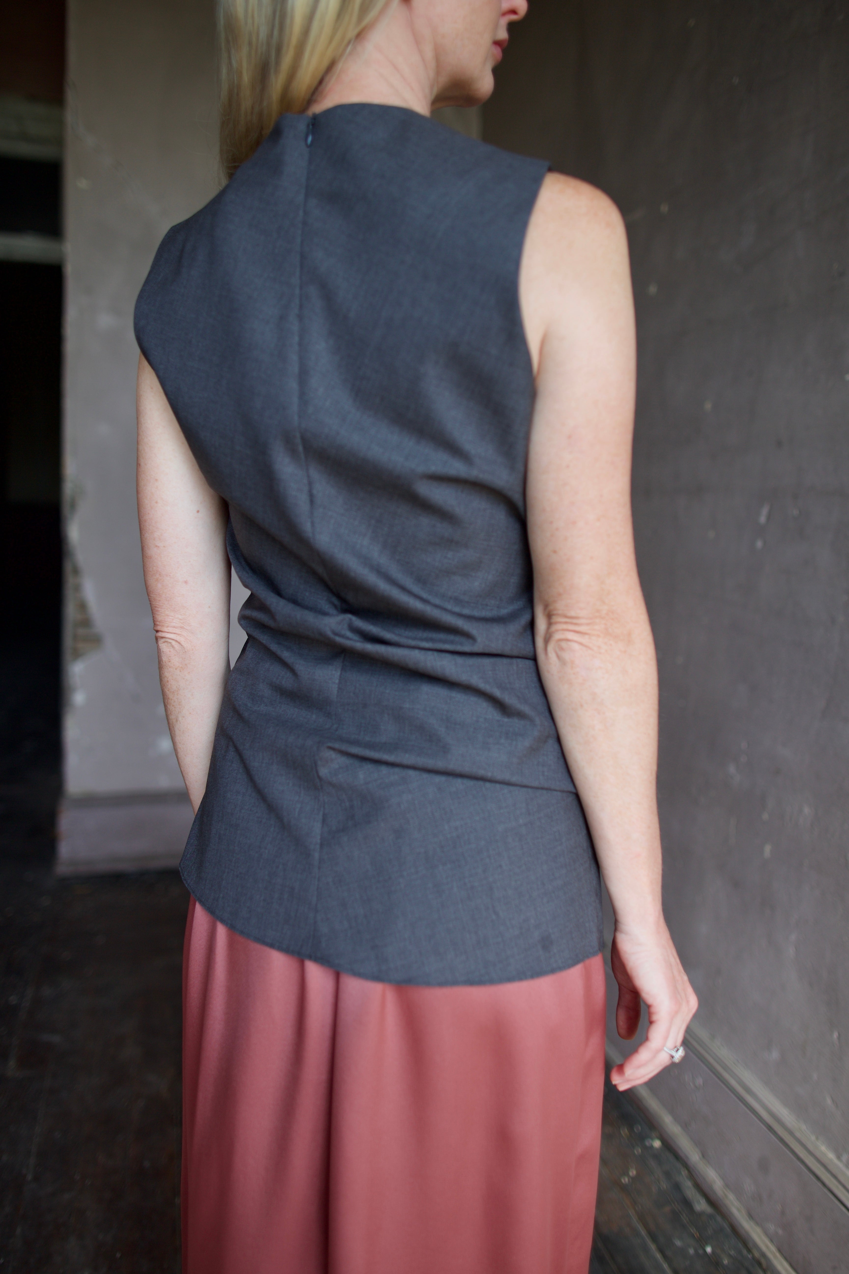Model wearing luxury designer Rohe sleeveless twisted top in dark grey combining refined tailoring with contemporary comfort and concealed back zip