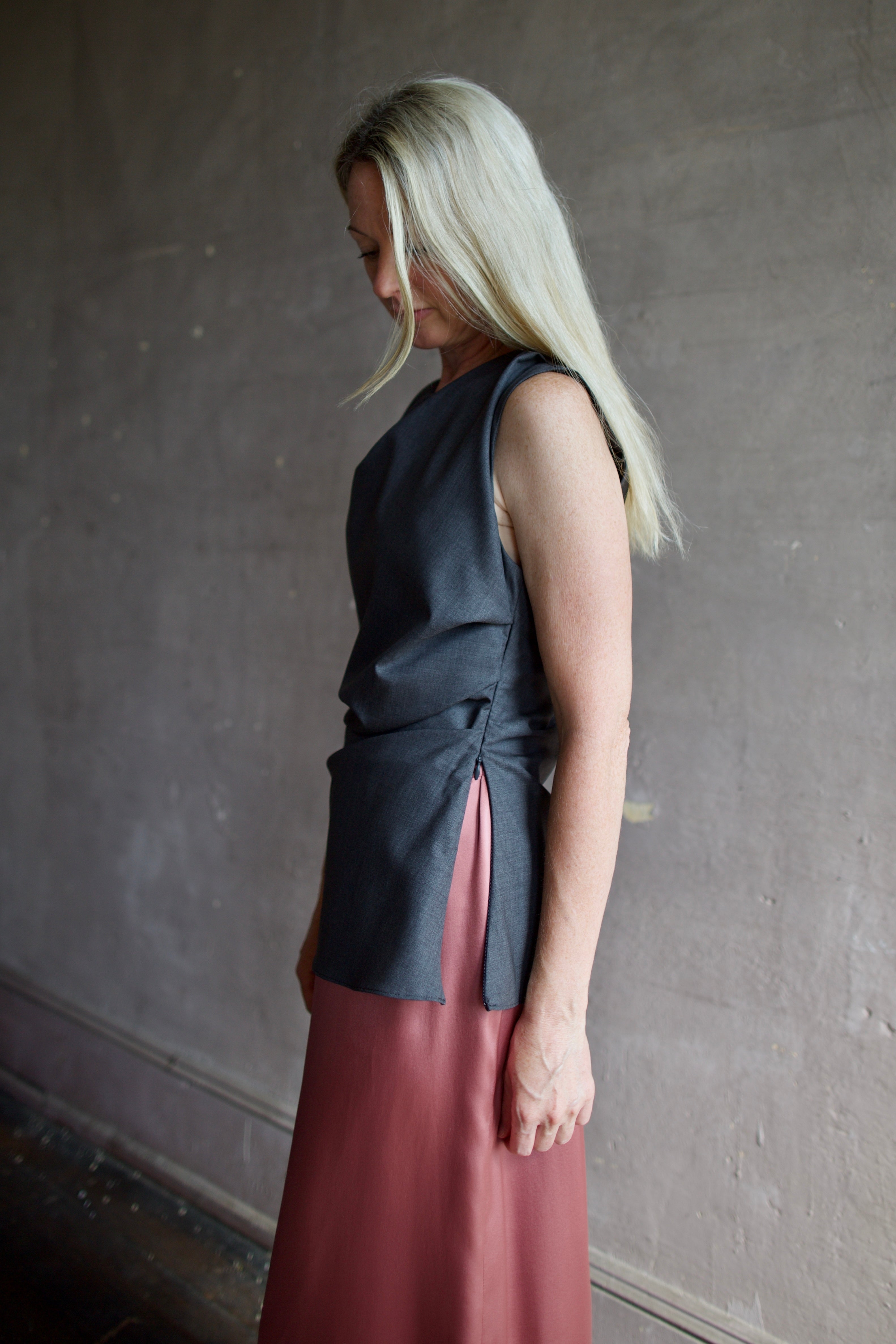 Model wearing luxury designer Rohe sleeveless twisted top in dark grey combining refined tailoring with side slit