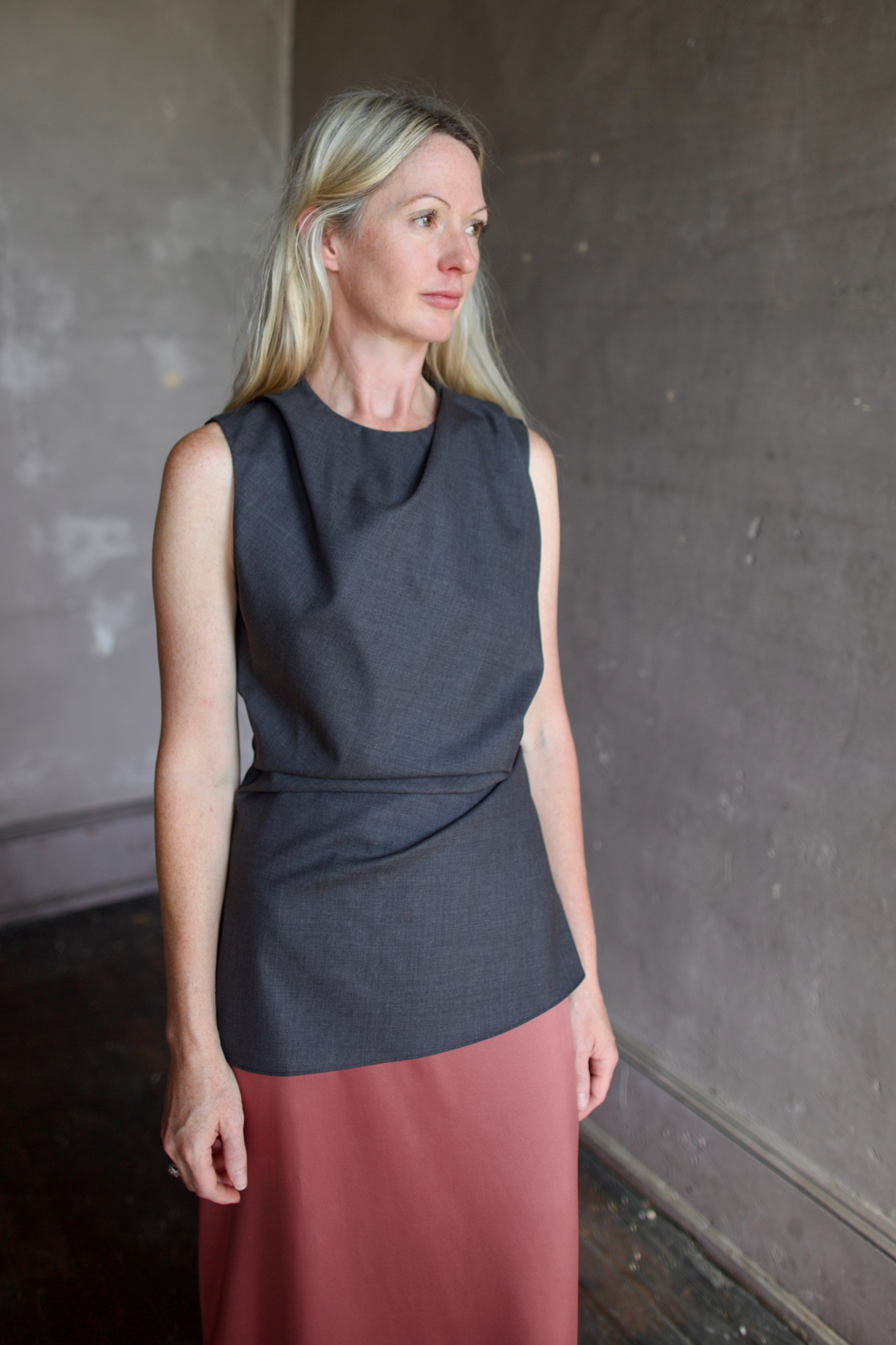 Model wearing luxury designer Rohe sleeveless twisted top in dark grey combining refined tailoring with contemporary comfort