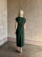 Mature woman wearing Sablyn Inez draped silk V-neck dark green midi dress with short cap sleeves made in USA