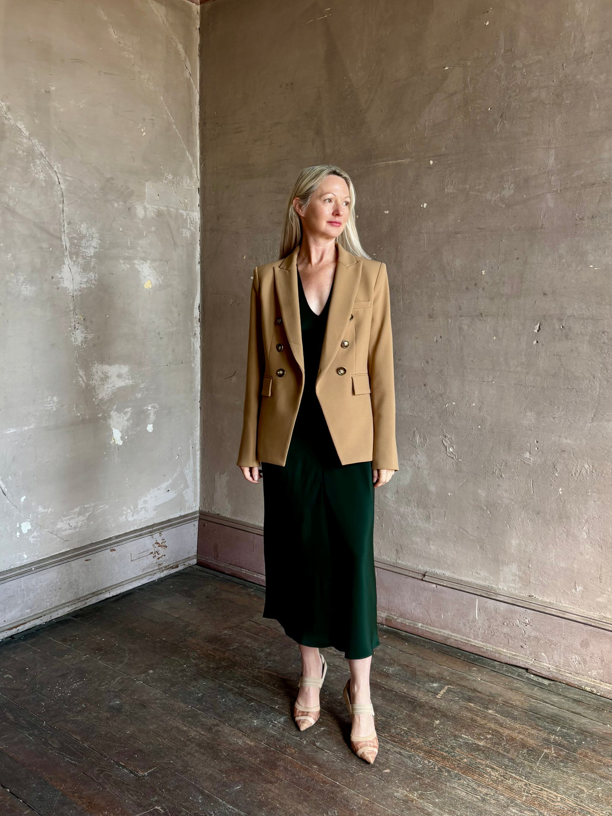 Mature woman wearing Sablyn Inez draped silk V-neck dark green midi dress with short cap sleeves made in USA