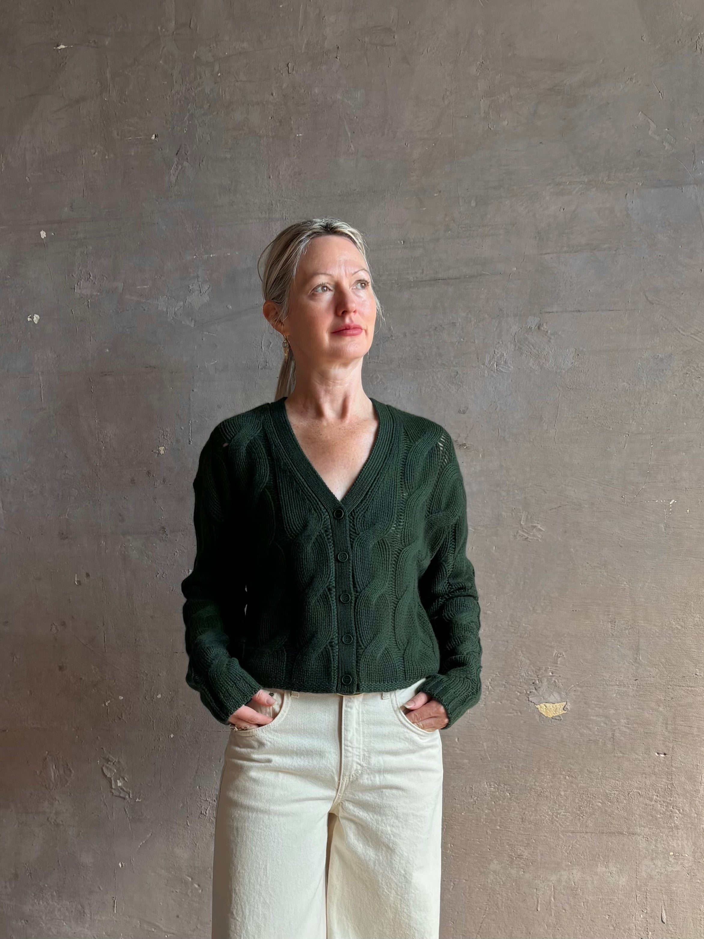 Mature woman wearing Sablyn Jolie dark green V-neck cropped cable-knit long sleeve cashmere cardigan sweater 