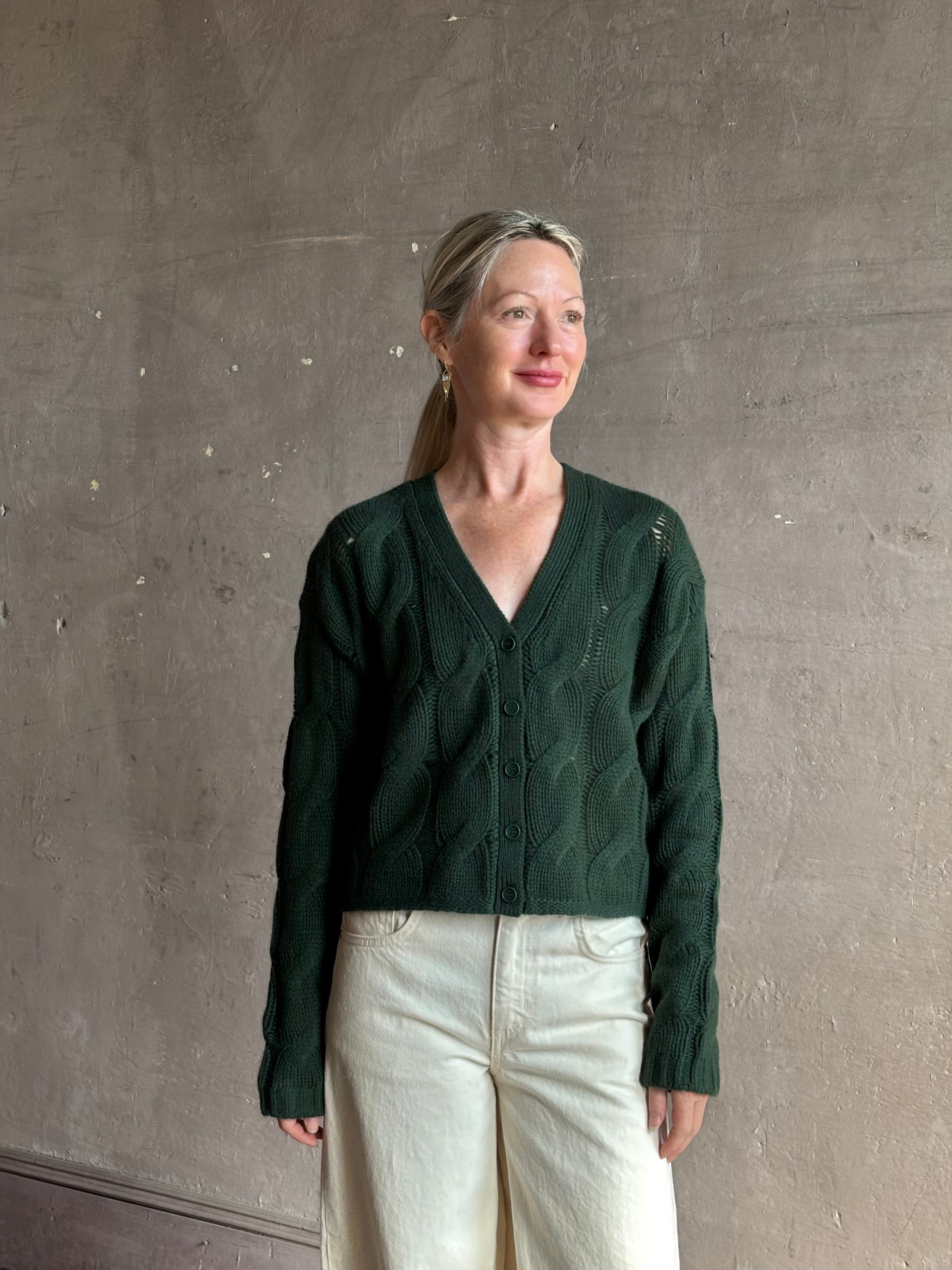 Mature woman wearing Sablyn Jolie dark green V-neck cropped cable-knit long sleeve cashmere cardigan sweater 