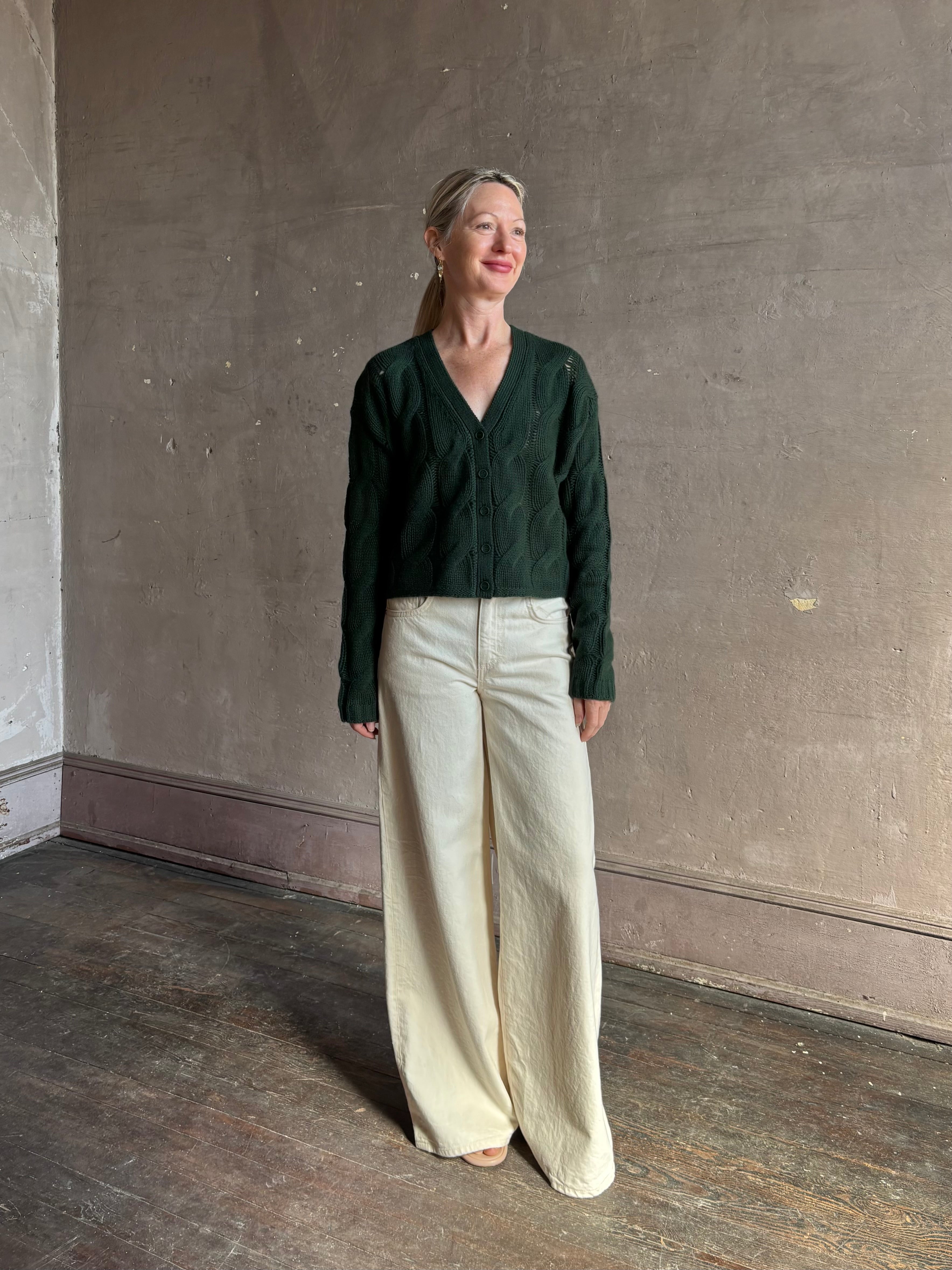 Mature woman wearing Sablyn Jolie dark green V-neck cropped cable-knit long sleeve cashmere cardigan sweater 