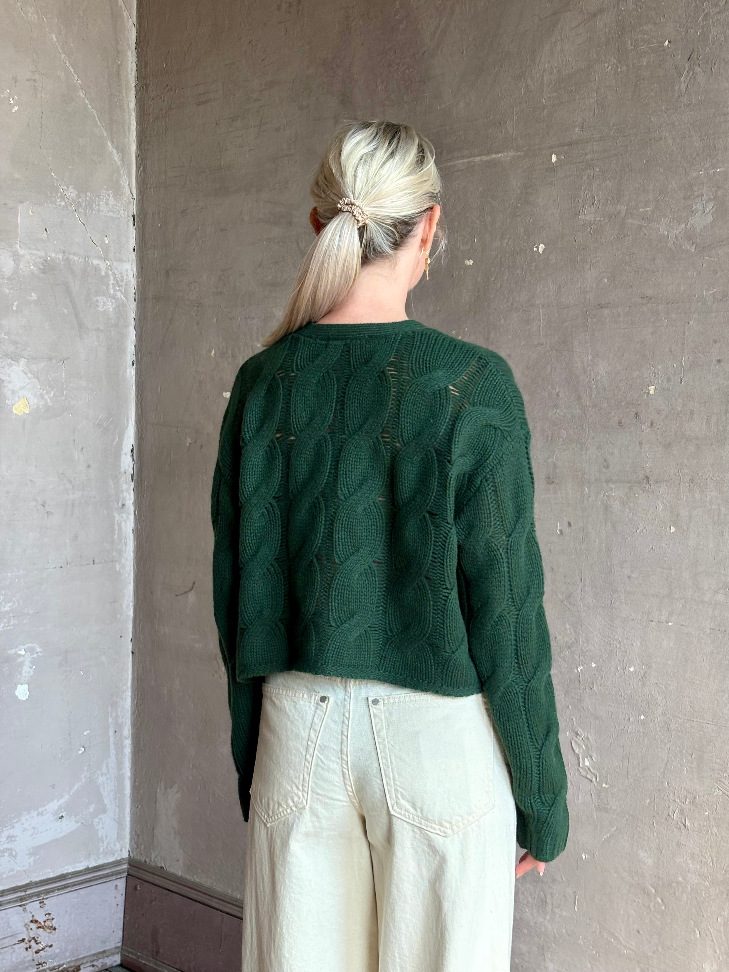 Mature woman wearing Sablyn Jolie dark green V-neck cropped cable-knit button front long sleeve cashmere cardigan 