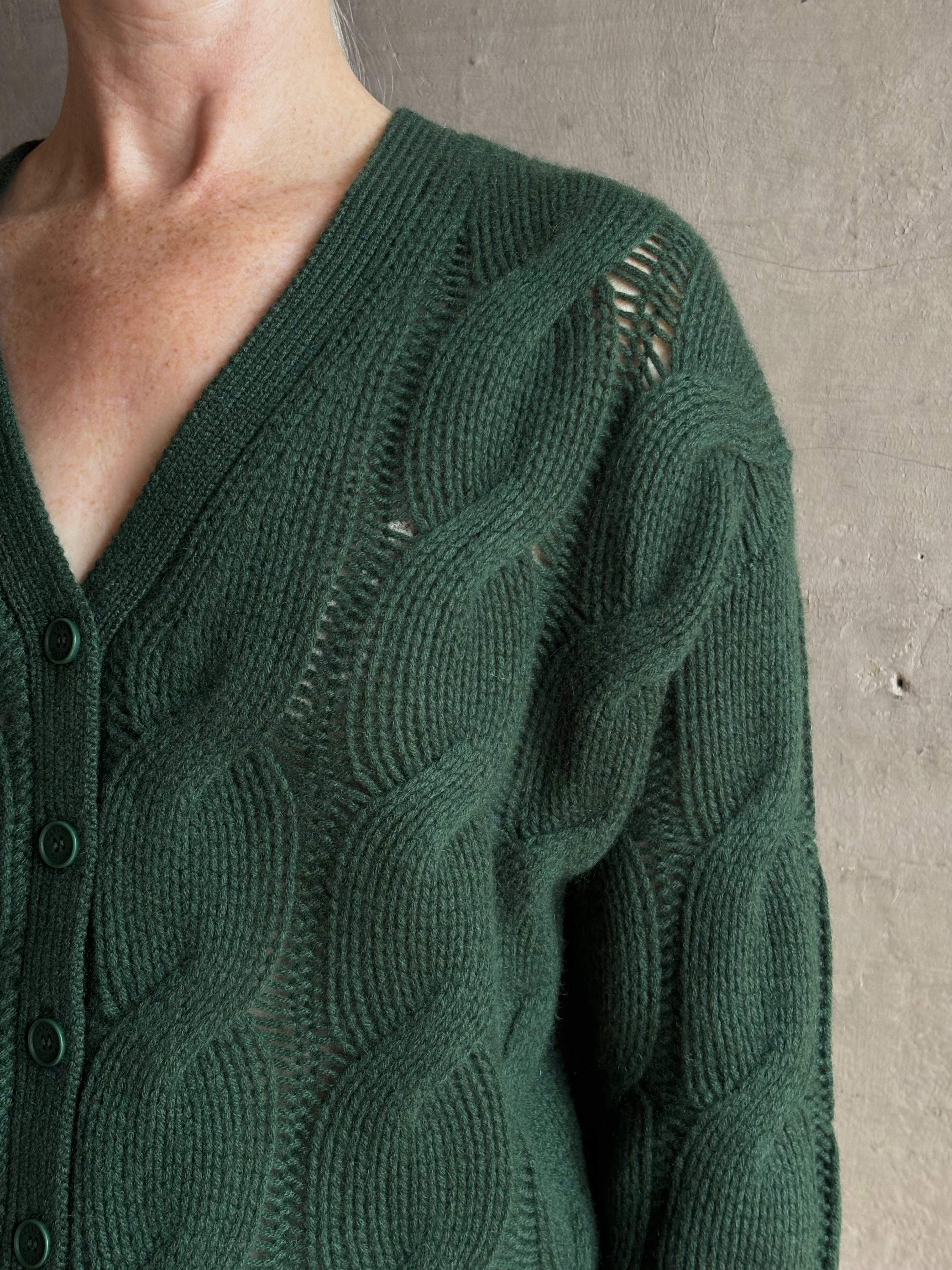 Mature woman wearing Sablyn Jolie dark green V-neck cropped cable-knit button front long sleeve cardigan 