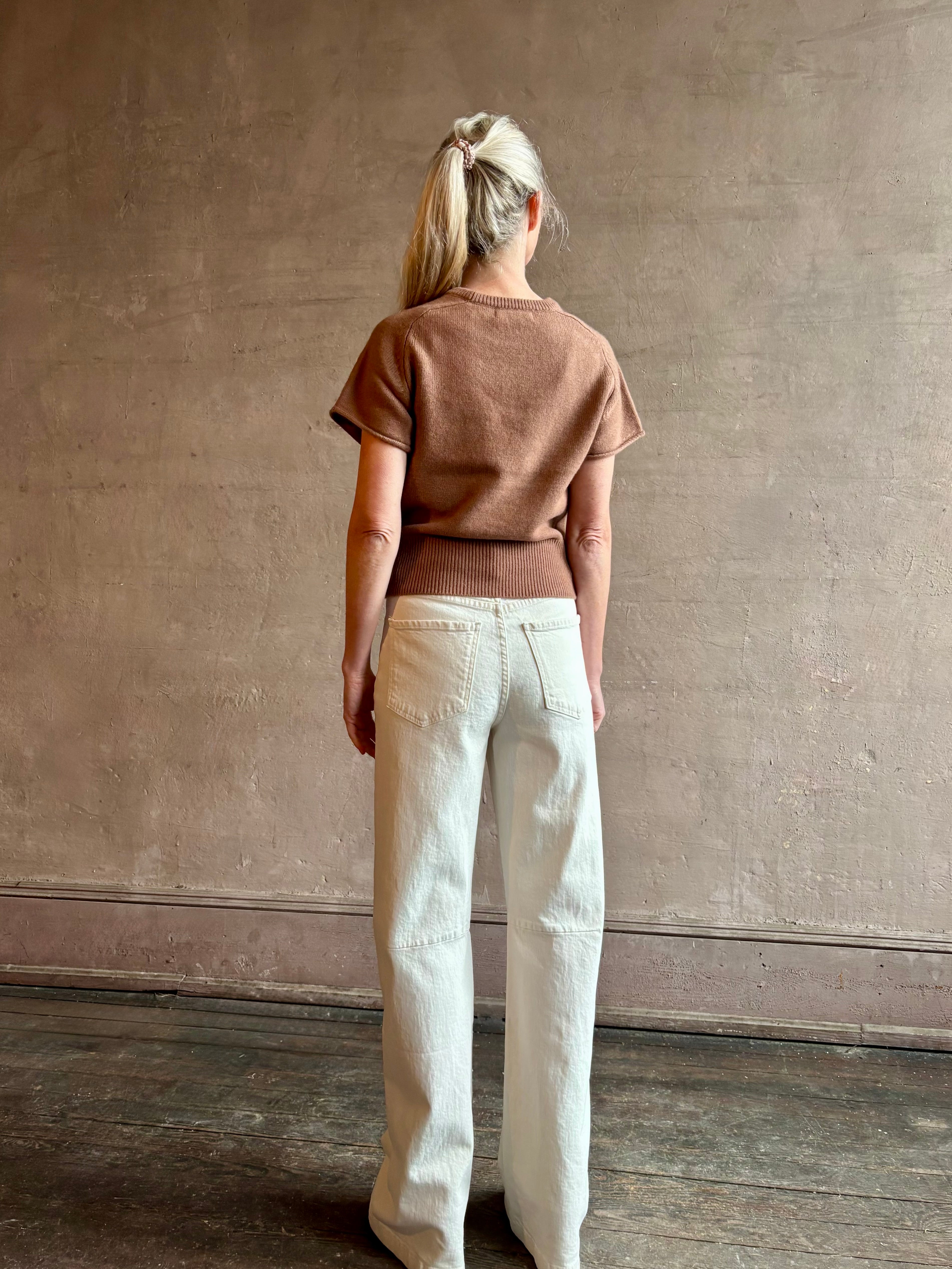 Woman wearing SABLYN Jones Saddle Raglan Cashmere Sweater in Prairie Sand with short sleeves and tailored waistband