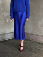 Mature woman wearing a vibrant royal blue silk bias cut midi skirt and matching cashmere knit sweater set