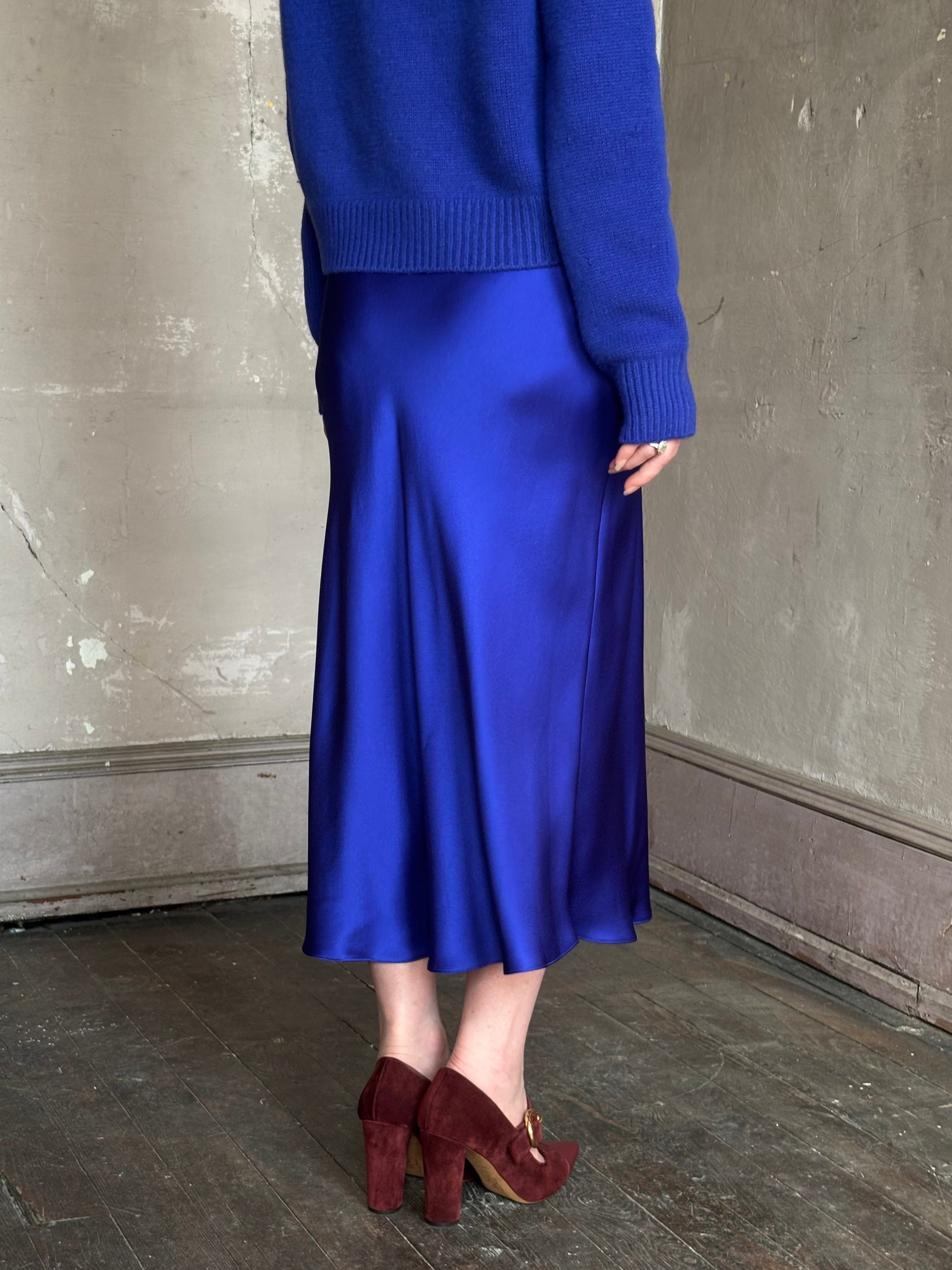 Mature woman wearing a vibrant royal blue silk bias cut midi skirt and matching cashmere knit sweater set