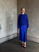Mature woman wearing a vibrant royal blue silk bias cut midi skirt and matching cashmere knit sweater set