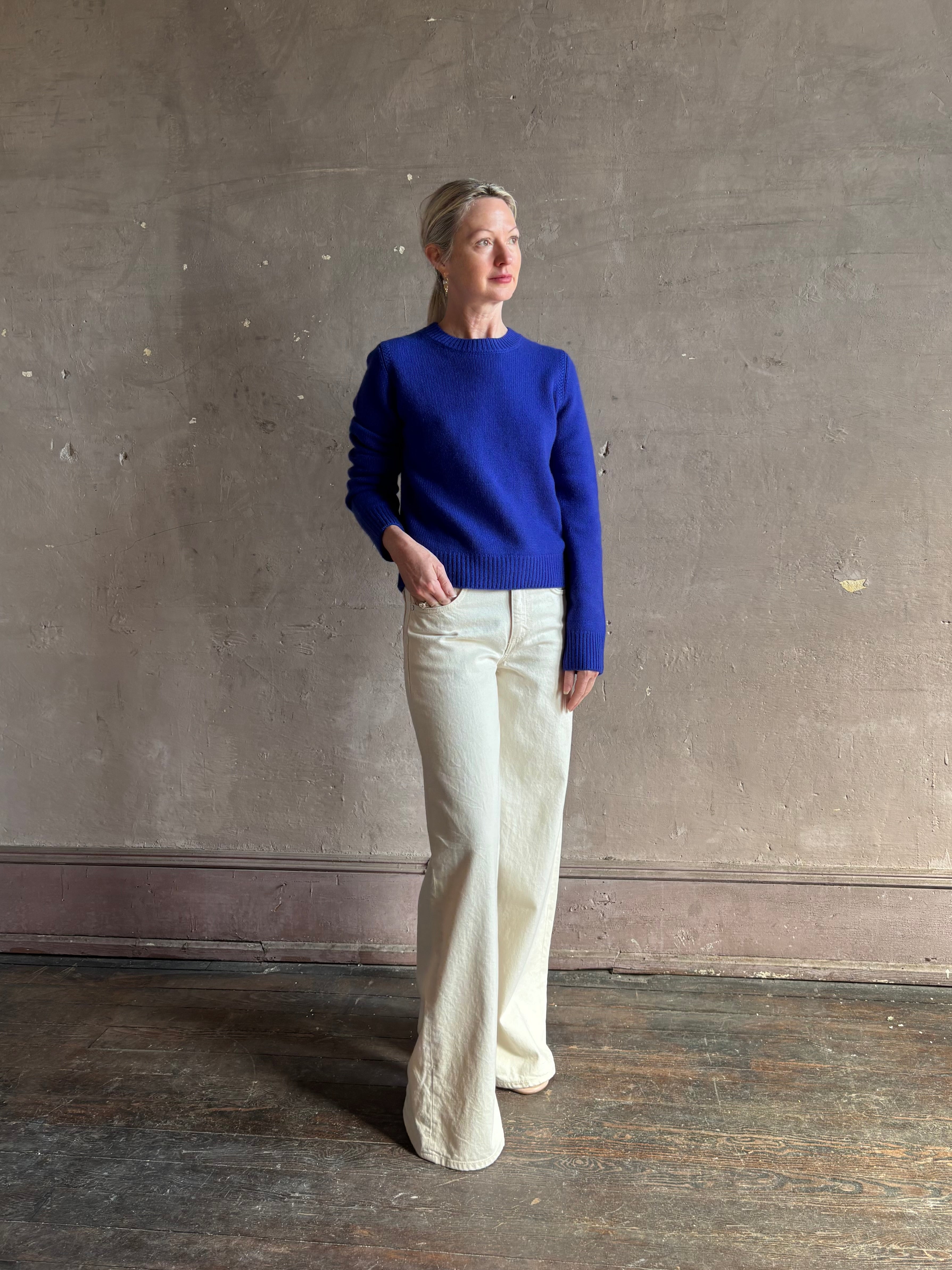 Mature woman wearing a vibrant cobalt blue Sablyn crewneck knit shrunken crewneck long sleeve cashmere sweater 