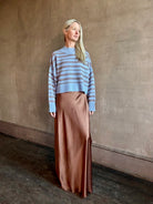 Woman wearing SABLYN Wells B Cropped Pullover Sweater in a french blue background and copper stripe