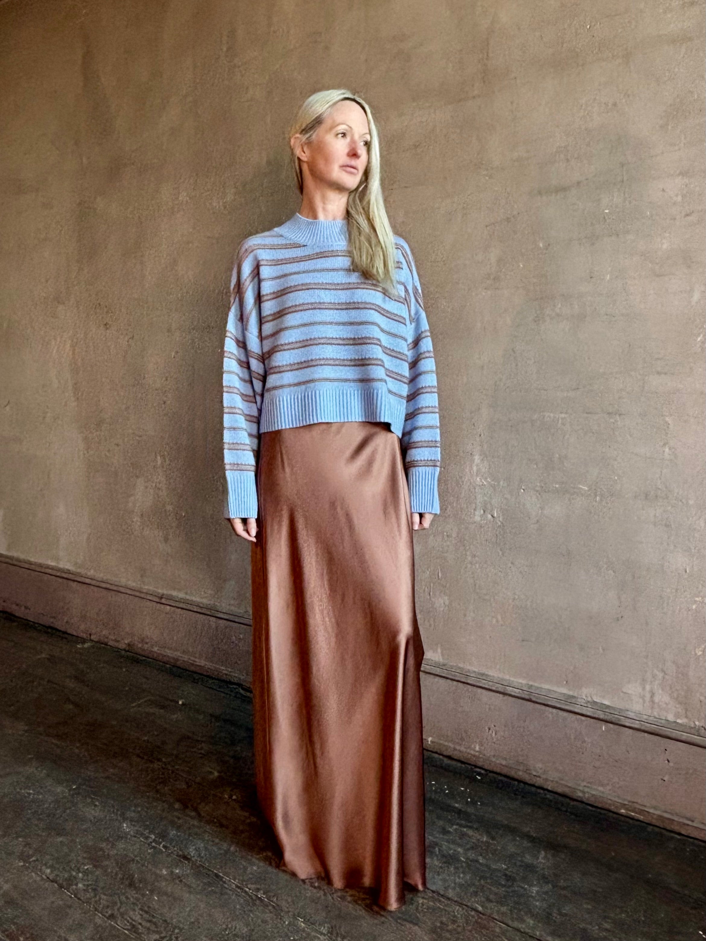 Woman wearing SABLYN Wells B Cropped Pullover Sweater in a french blue background and copper stripe