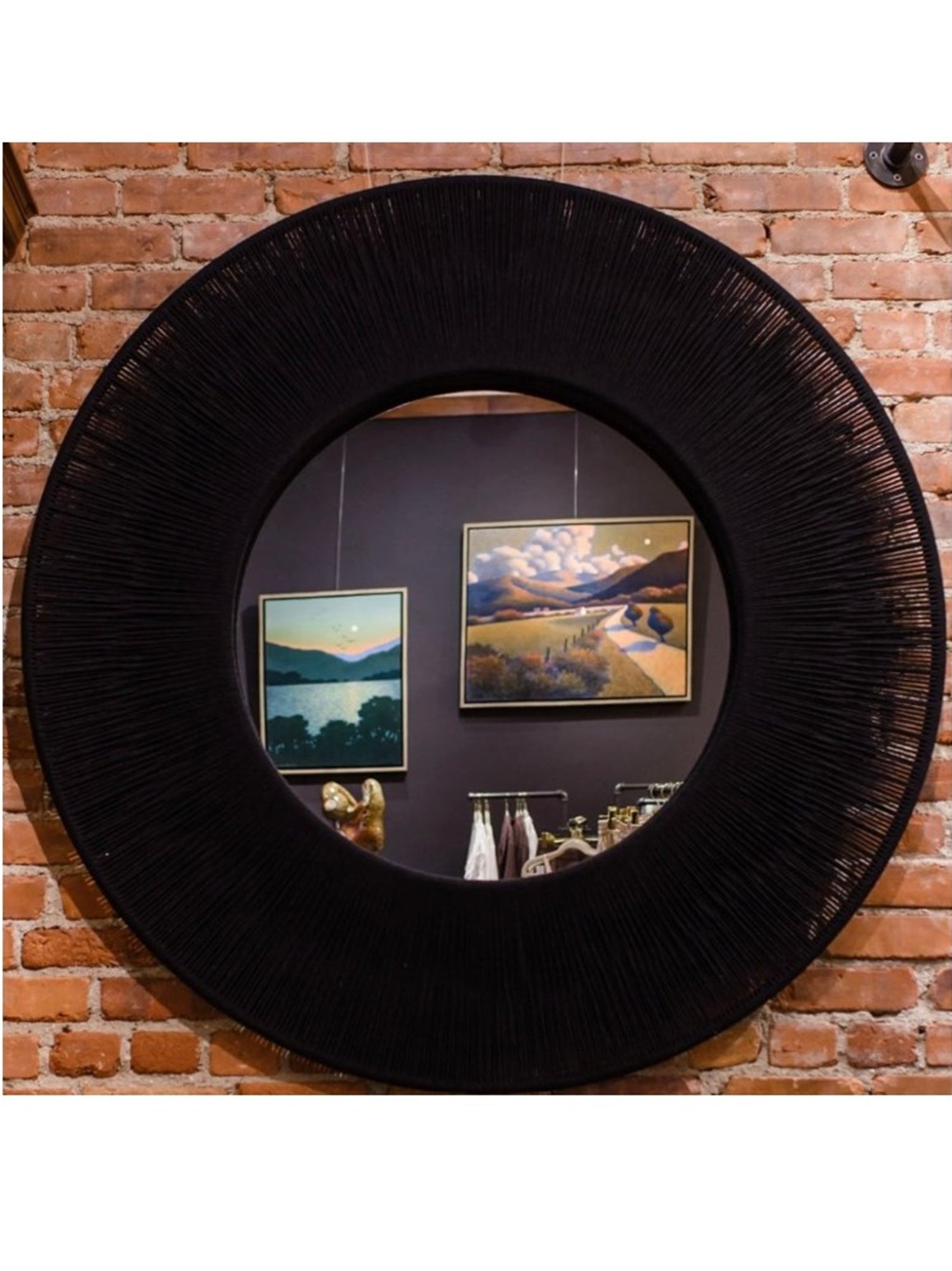 A large round mirrored wall decoration with intricate woven black rope perimeter frame.