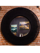 A large round mirrored wall decoration with intricate woven black rope perimeter frame.