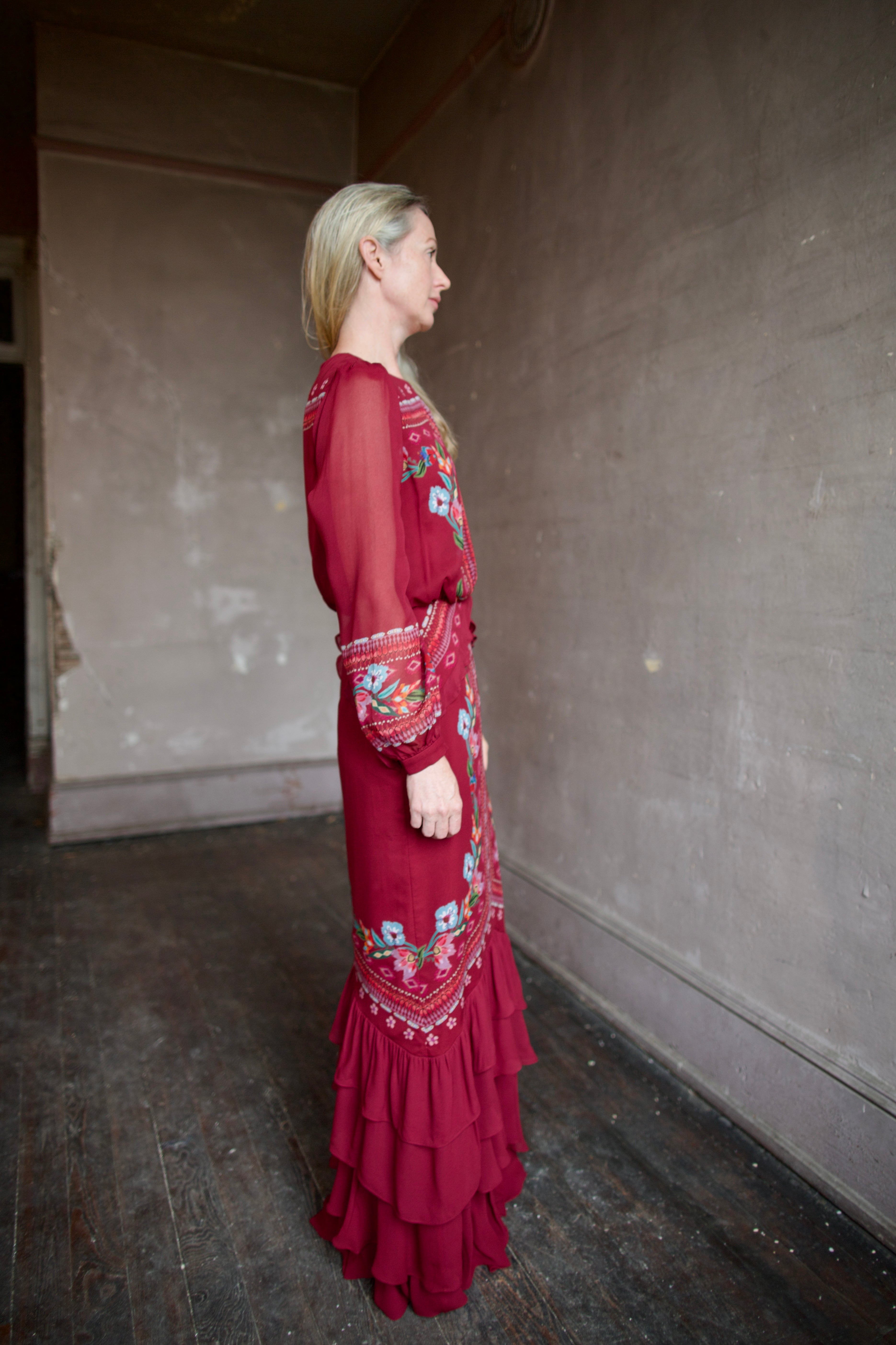 Mature woman wearing sophisticated Saloni Isa Long-C silk burgundy maxi Dress in Cordia Vines with long sleeves, delicate ruffle details and intricate floral pattern