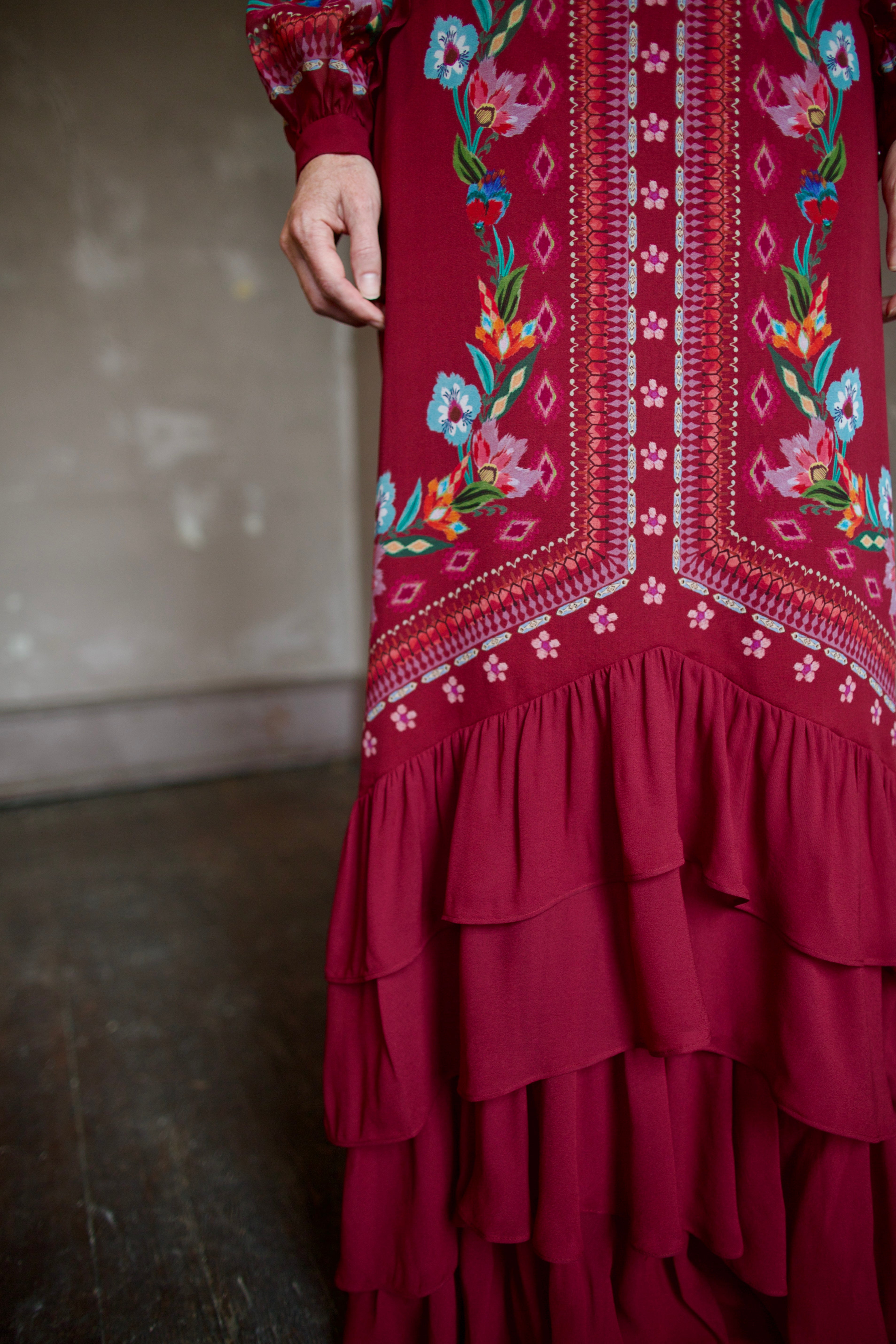 Mature woman wearing sophisticated Saloni Isa Long-C silk burgundy maxi Dress in Cordia Vines with long sleeves, delicate ruffle details and intricate floral pattern
