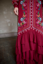 Mature woman wearing sophisticated Saloni Isa Long-C silk burgundy maxi Dress in Cordia Vines with long sleeves, delicate ruffle details and intricate floral pattern