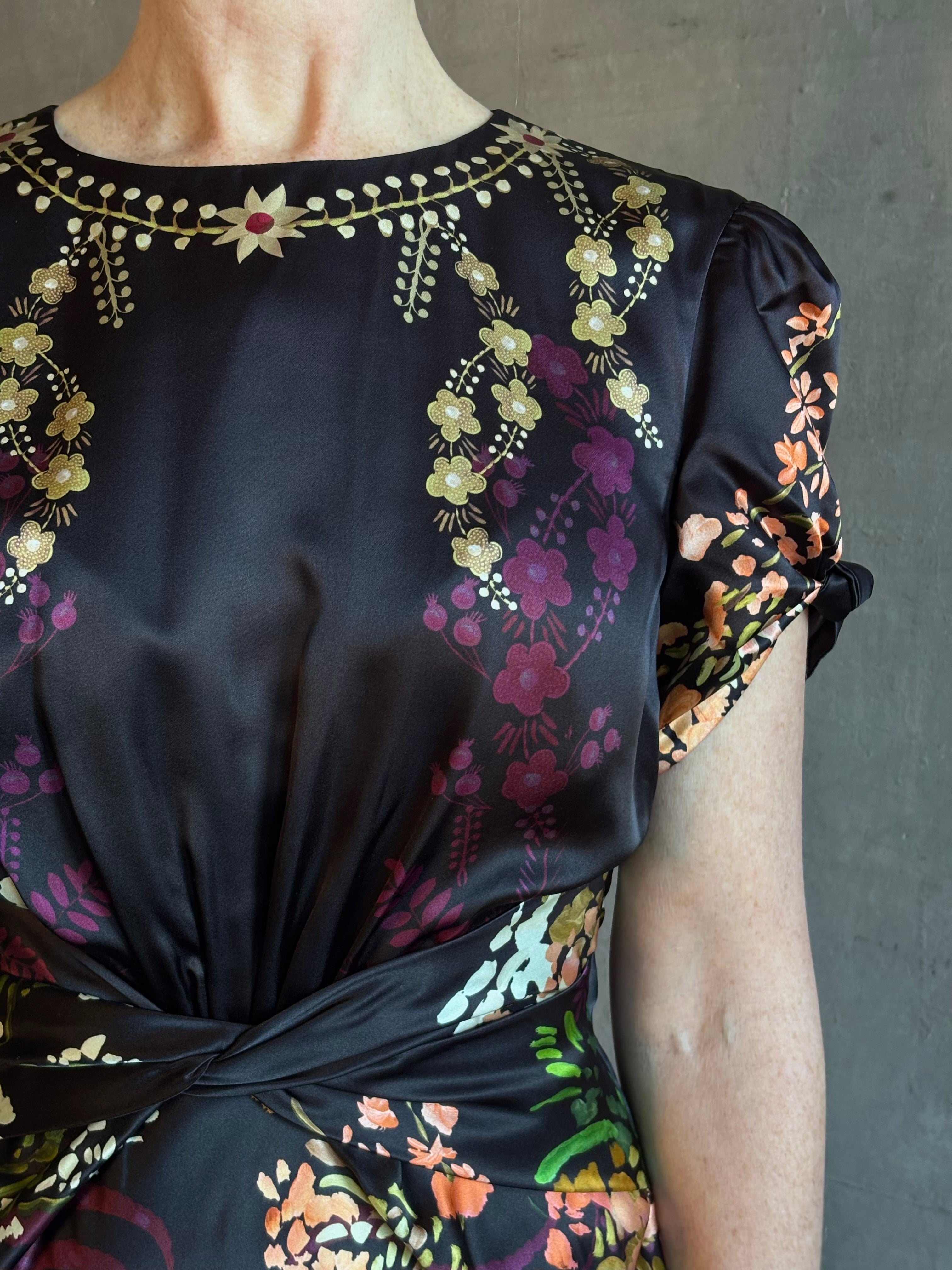 Mature woman wearing Saloni's Gwen C Dress in Equinox Plmt silk blend fit-and-flare silhouette cummerbund waist. Botanical, structured occasion elegance.
