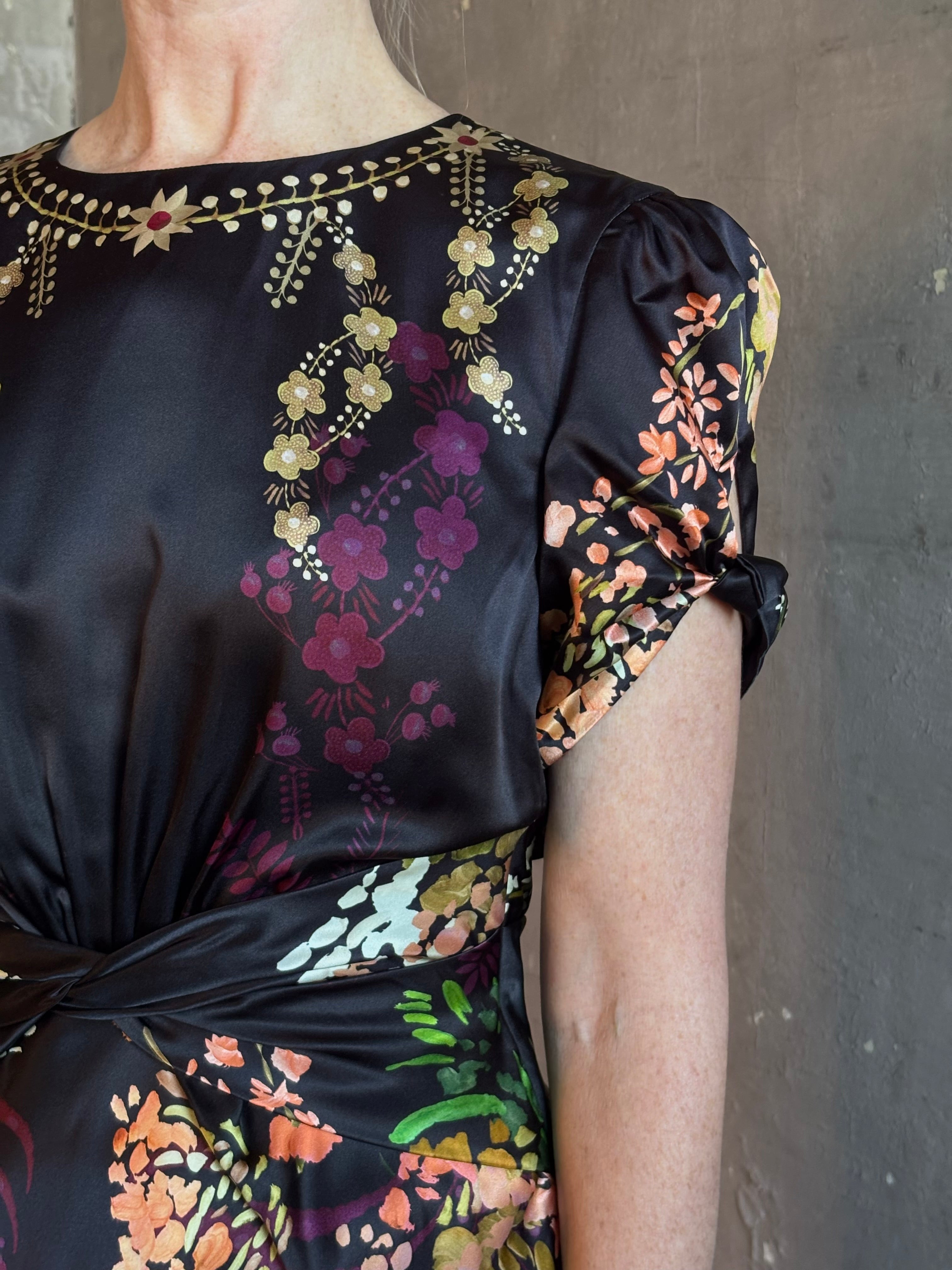 Mature woman wearing Saloni's Gwen C Dress in Equinox Plmt silk blend fit-and-flare silhouette cummerbund waist. Botanical, structured occasion elegance.