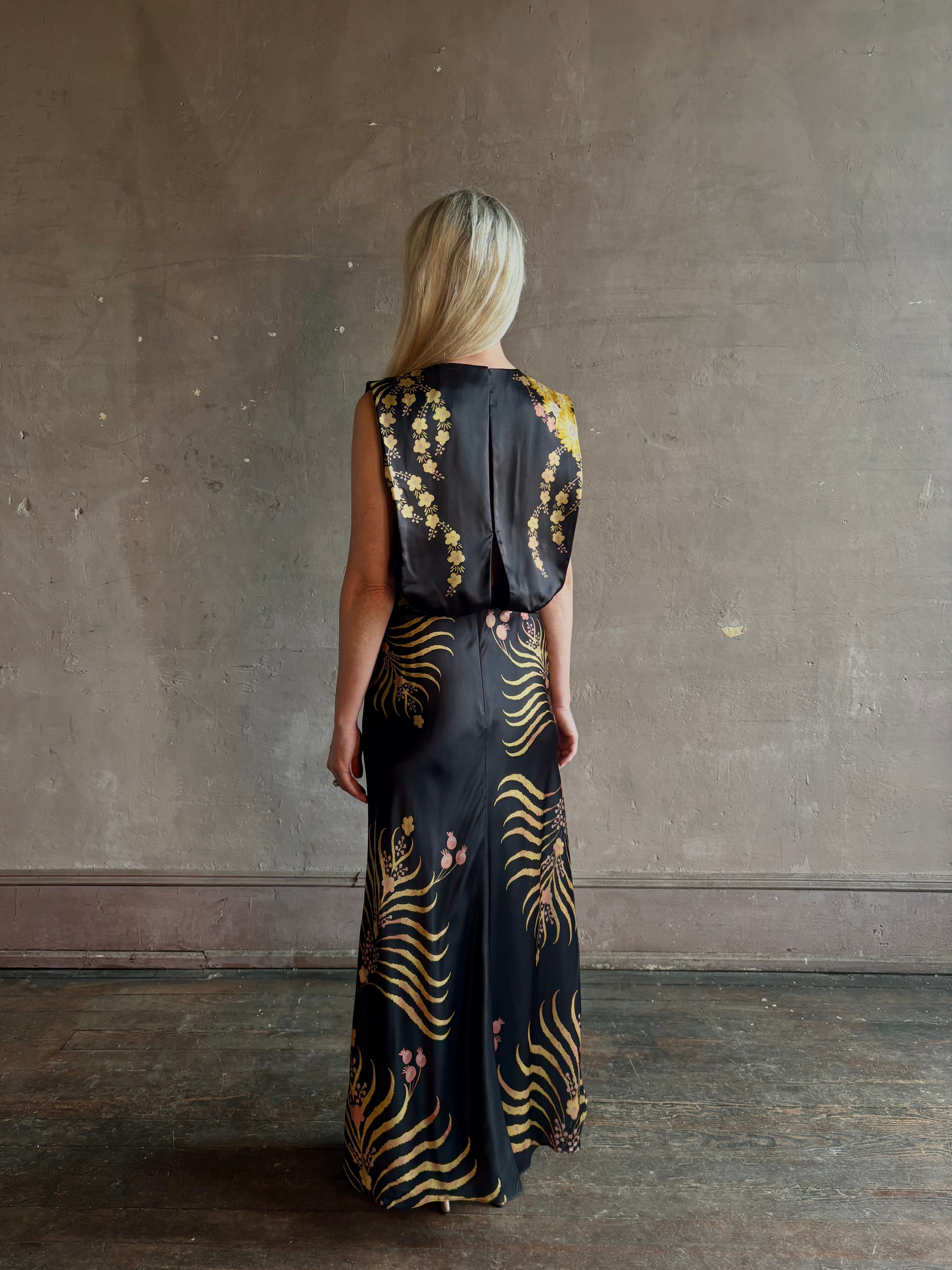 Mature woman wearing Saloni Gwen Dress in Golden Palm semi-open back gathered waist black with yellow and pink print evening gown
