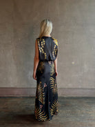 Mature woman wearing Saloni Gwen Dress in Golden Palm semi-open back gathered waist black with yellow and pink print evening gown