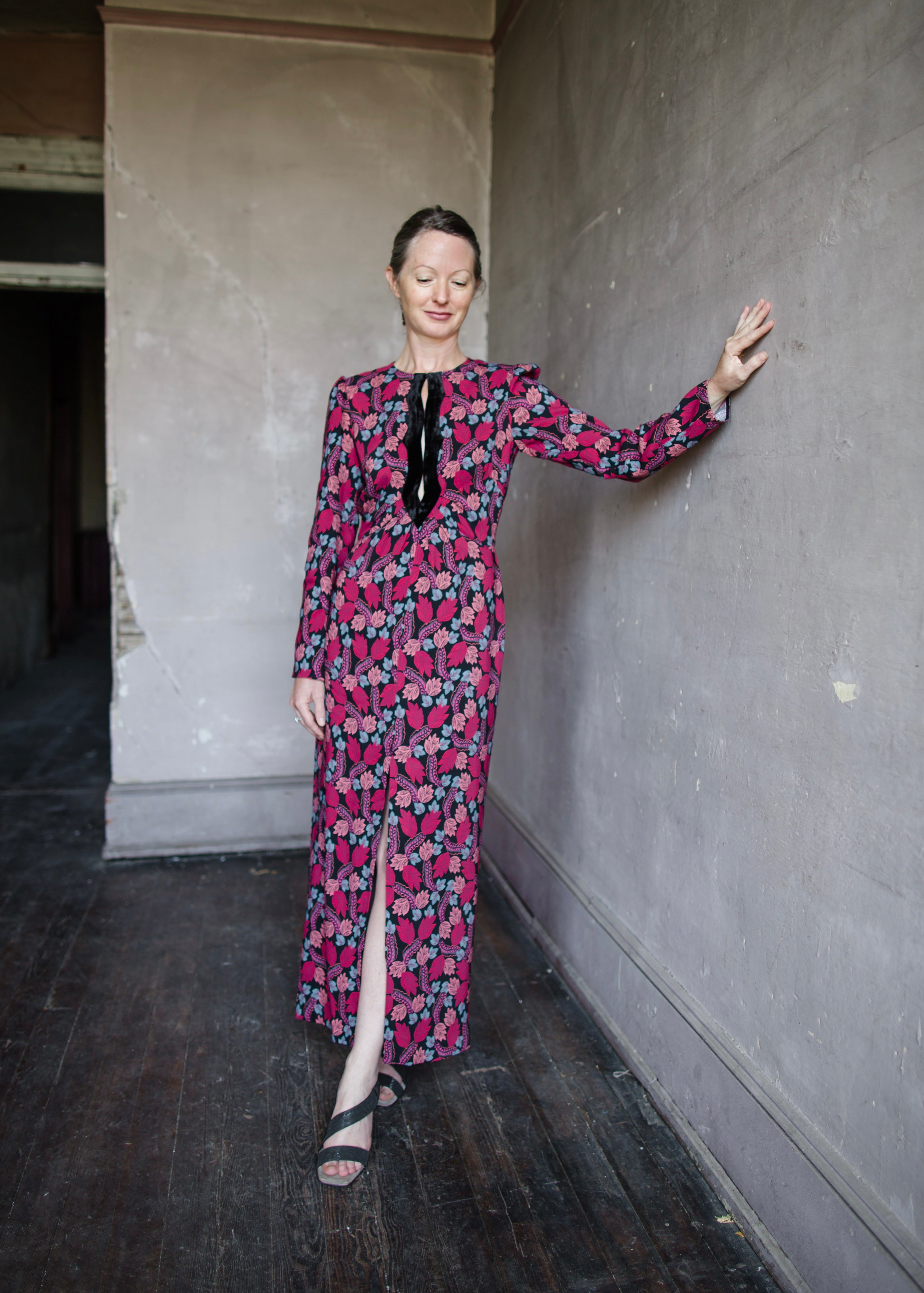 Image featuring a woman wearing the Jinx-C silk dress by Saloni with a crew neckline, long sleeves, and velvet trim cutouts down the front autumnal print