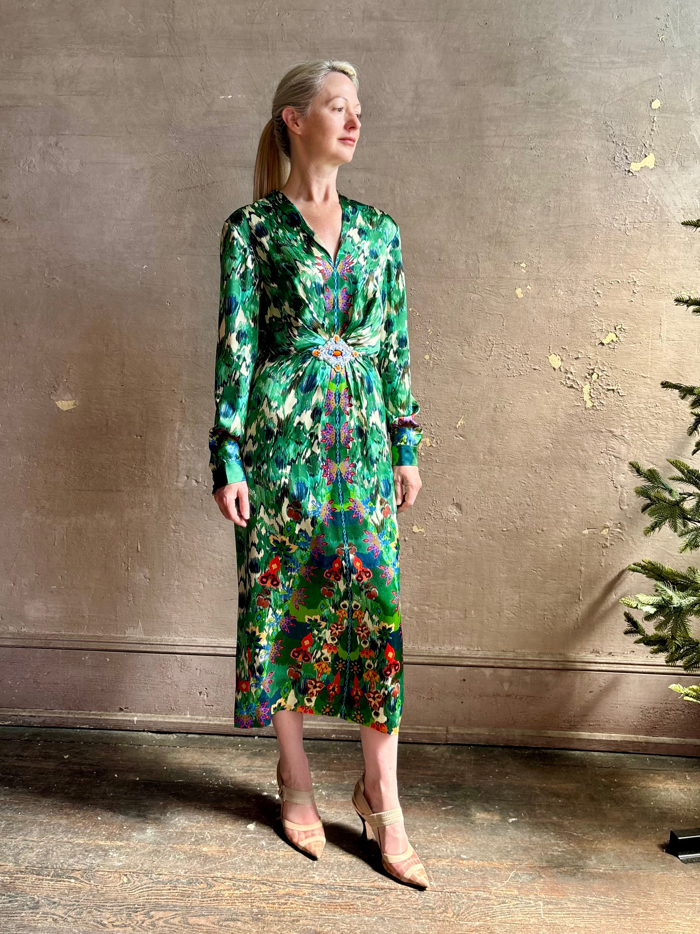 Mature woman wearing Saloni Mya silk long sleeve green floral midi dress with  broach gathered waist V-neck