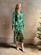 Mature woman wearing Saloni Mya silk long sleeve green floral midi dress with  broach gathered waist V-neck
