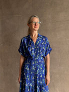 Woman wearing Saloni silk maxi Riya dress with short sleeves bouson top drop waist v-neck button front cobalt