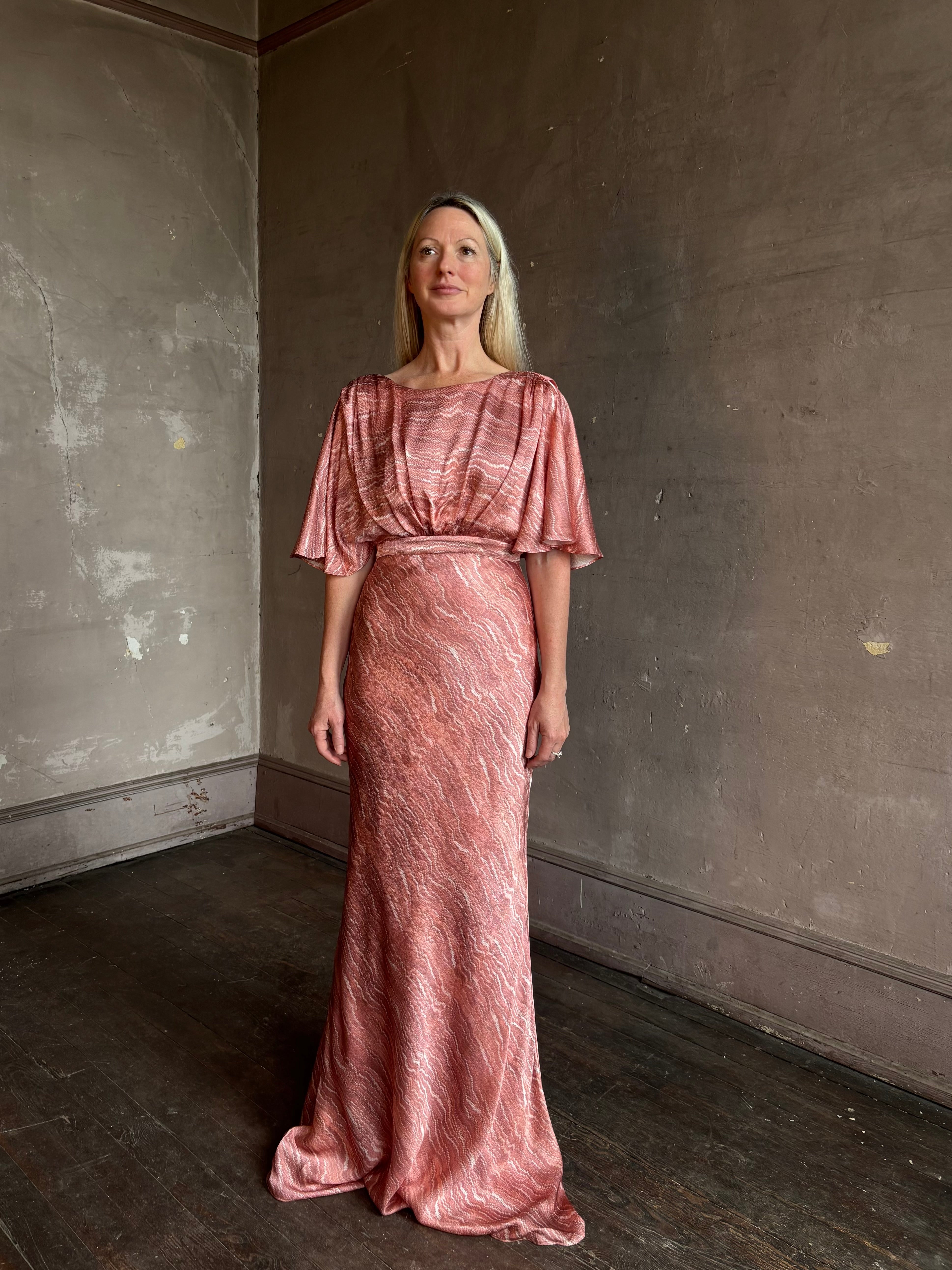 Mature woman wearing Saloni silk Winona Dress in Blush Marbling print V-back detail short sleeves empire waist Romantic occasion gown