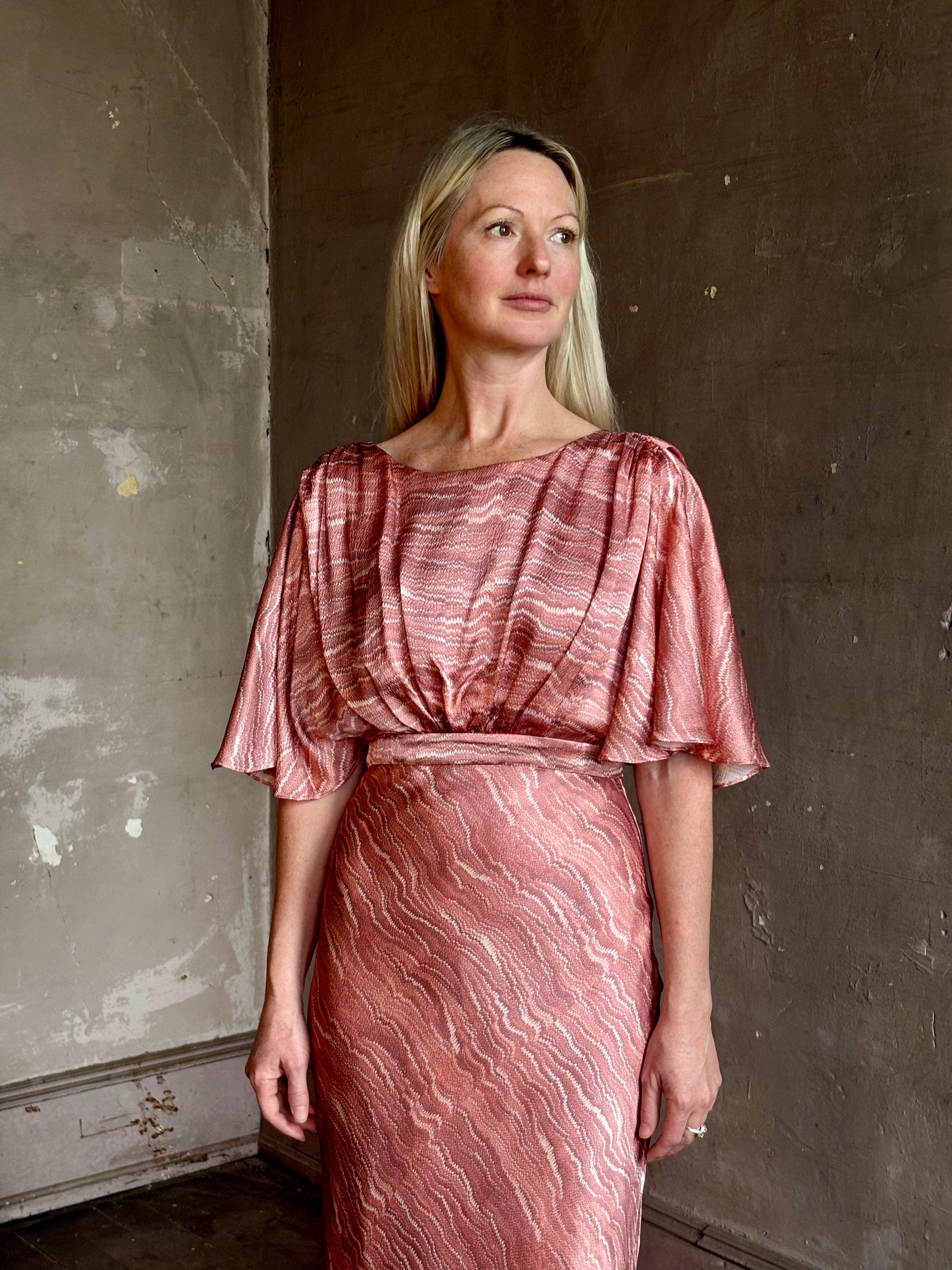 Mature woman wearing Saloni silk Winona Dress in Blush Marbling print V-back detail short sleeves empire waist Romantic occasion gown