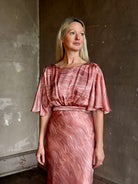 Mature woman wearing Saloni silk Winona Dress in Blush Marbling print V-back detail short sleeves empire waist Romantic occasion gown