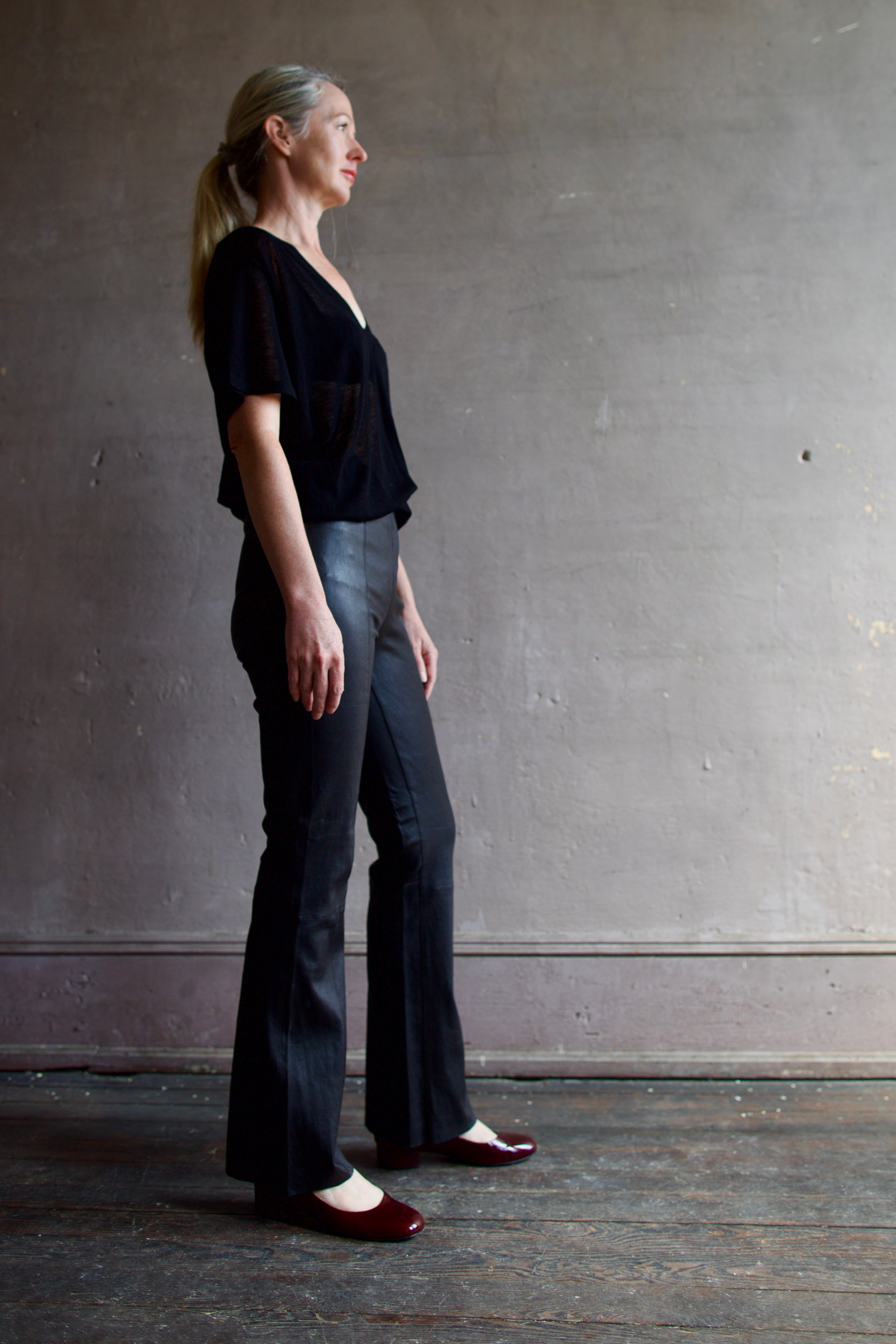 Model wearing SPRWMN Black Ankle Flare Leather Pants - Designer Mid-Rise Stretch Leather