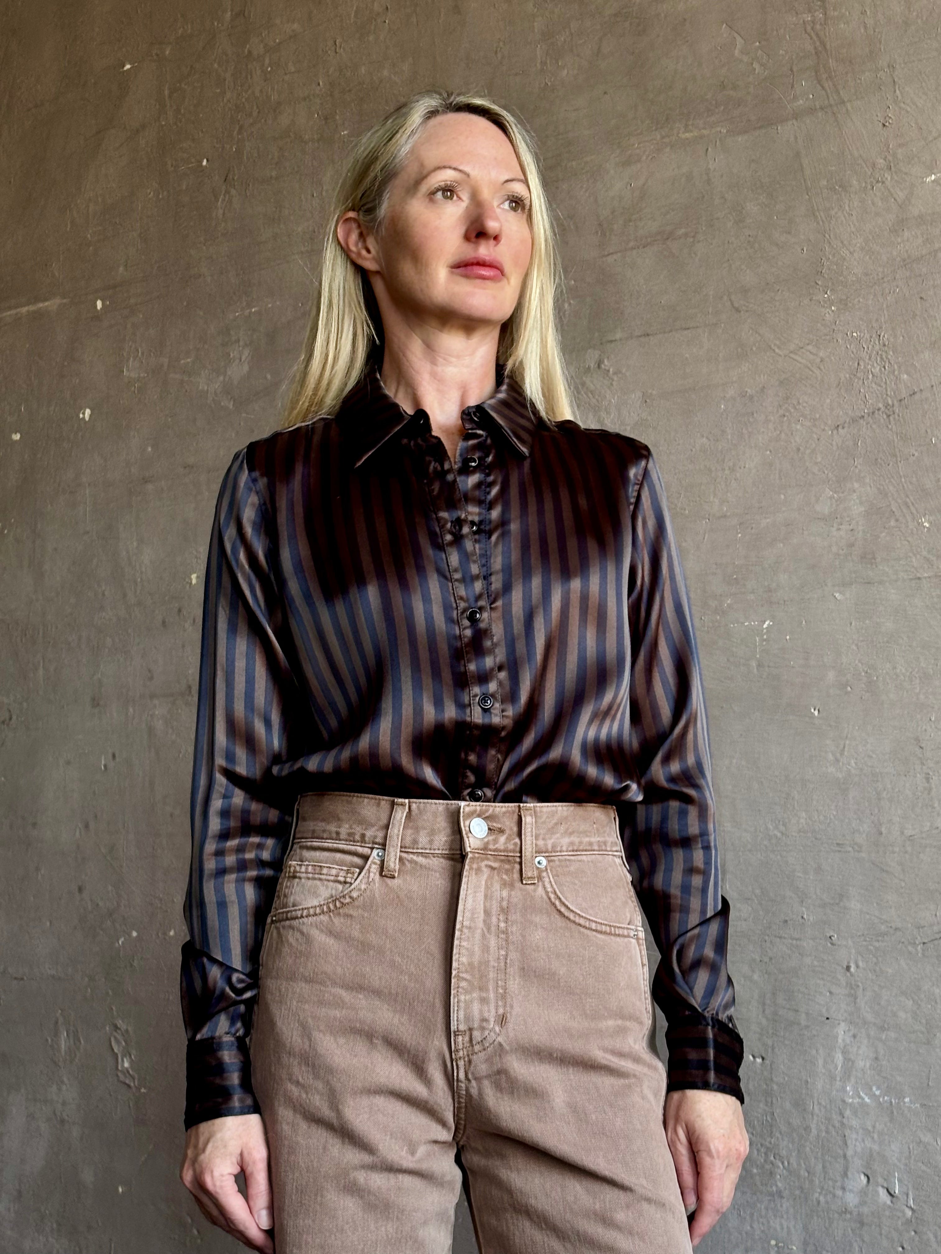 Image of woman wearing luxury brand SPRWMN Fonda silk button up shirt in a black and brown stripe modern classic.