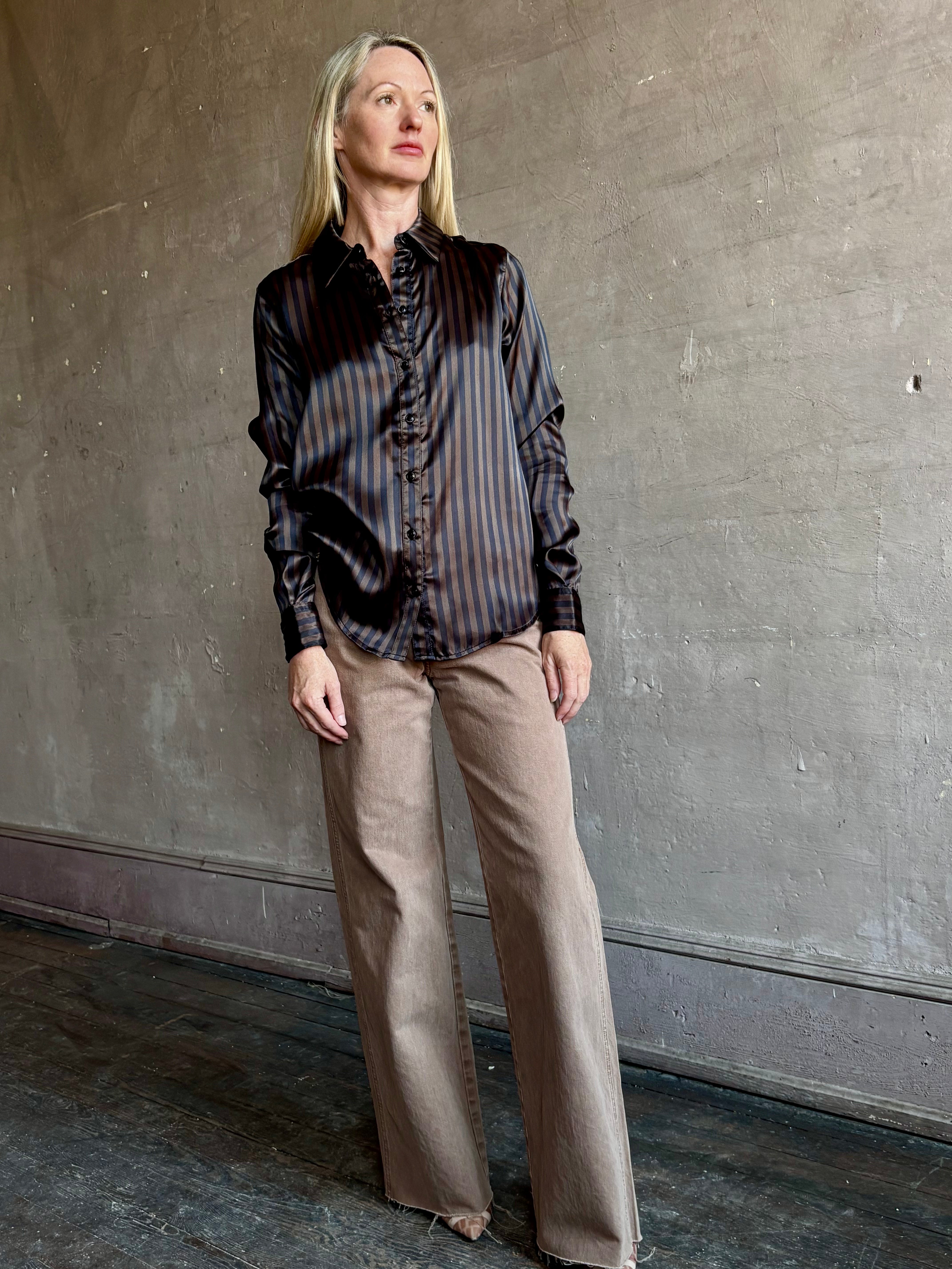 Image of woman wearing luxury brand SPRWMN Fonda silk button up shirt in a black and brown stripe modern classic.