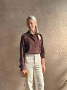Mature woman wearing elevated casual wear button front Fonda top by SPRWMN in chocolate brown cashmere with long sleeves and a collar