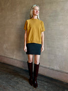 Image of woman wearing SPRWMN Mia cashmere skirt in charcoal grey with a Rachel Comey yellow sweatshirt and tall boots 