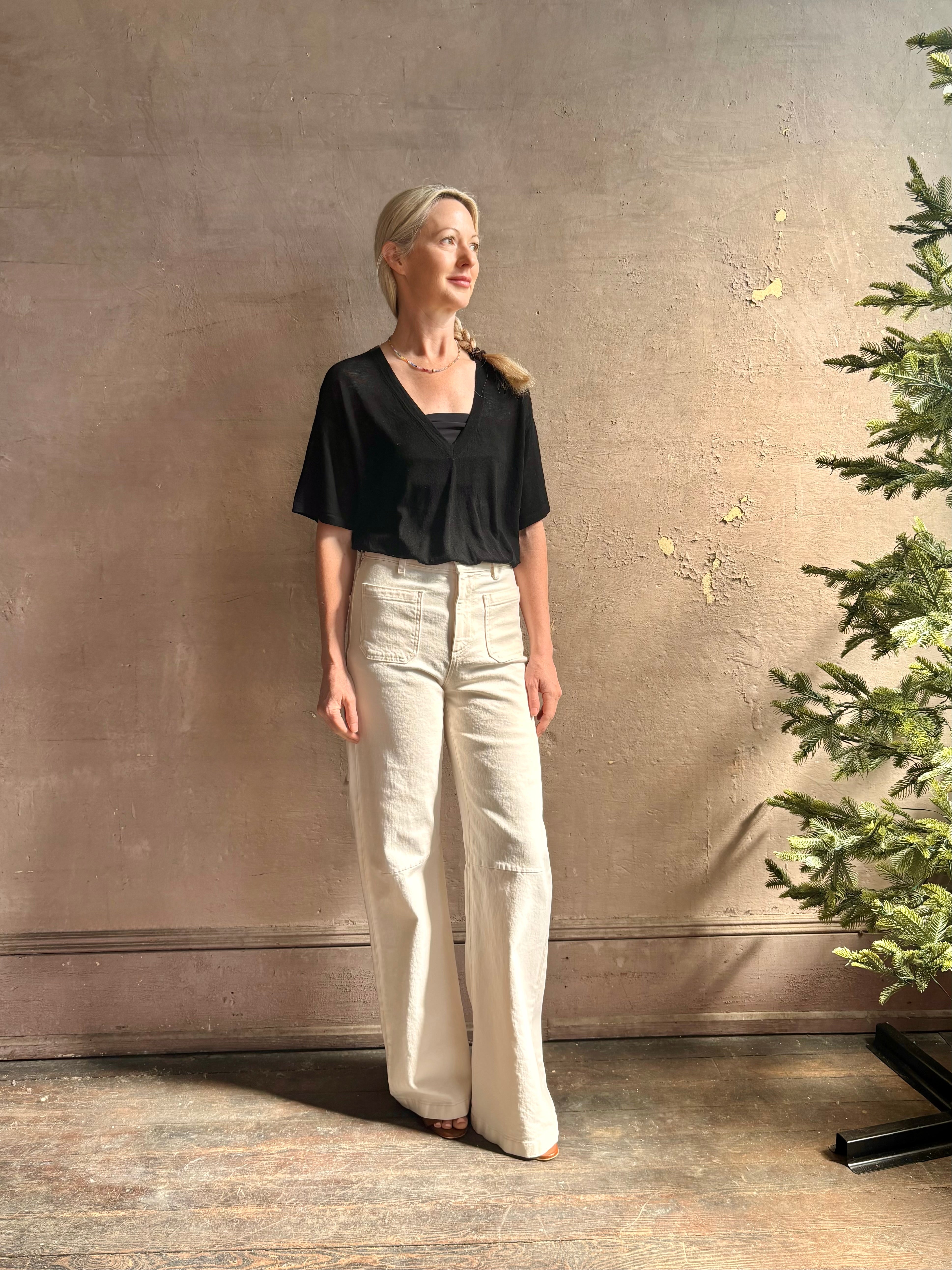 Mature woman wearing V Neck Tee from SPRWMN rendered in a timeless black and crafted from 100% premium sheer wool with fluid draping and short sleeve