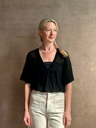 Mature woman wearing V Neck Tee from SPRWMN rendered in a timeless black and crafted from 100% premium sheer wool with fluid draping and short sleeve